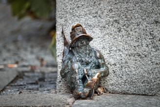 Bronze dwarf statue wearing a hat and holding a tool