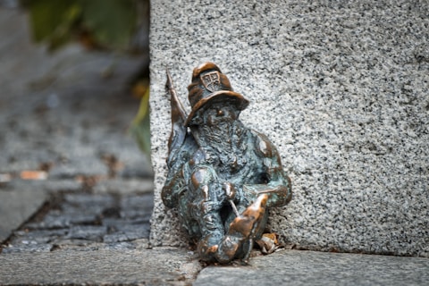 Bronze dwarf statue wearing a hat and holding a tool