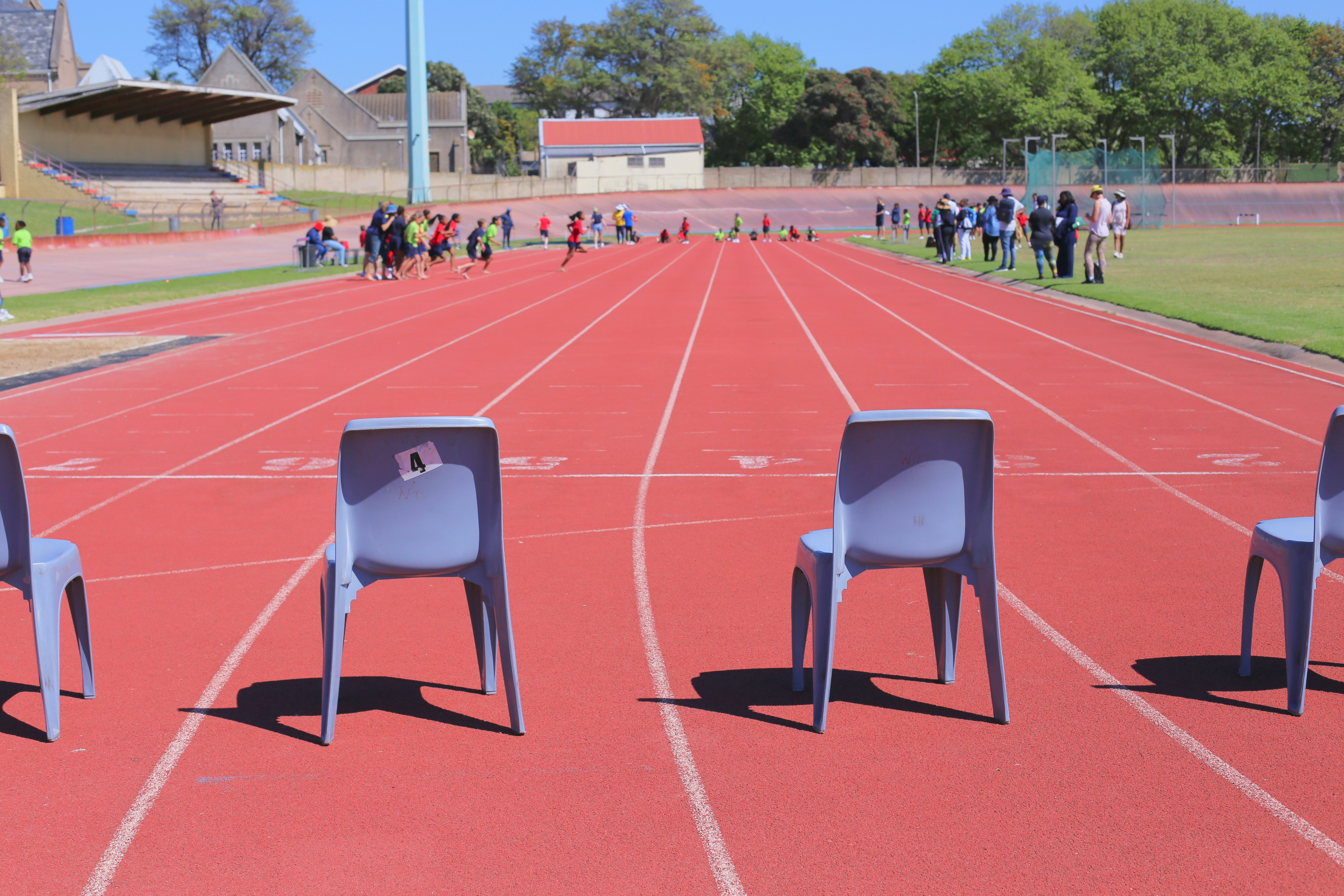 Athletes running on a track with chairs in foreground