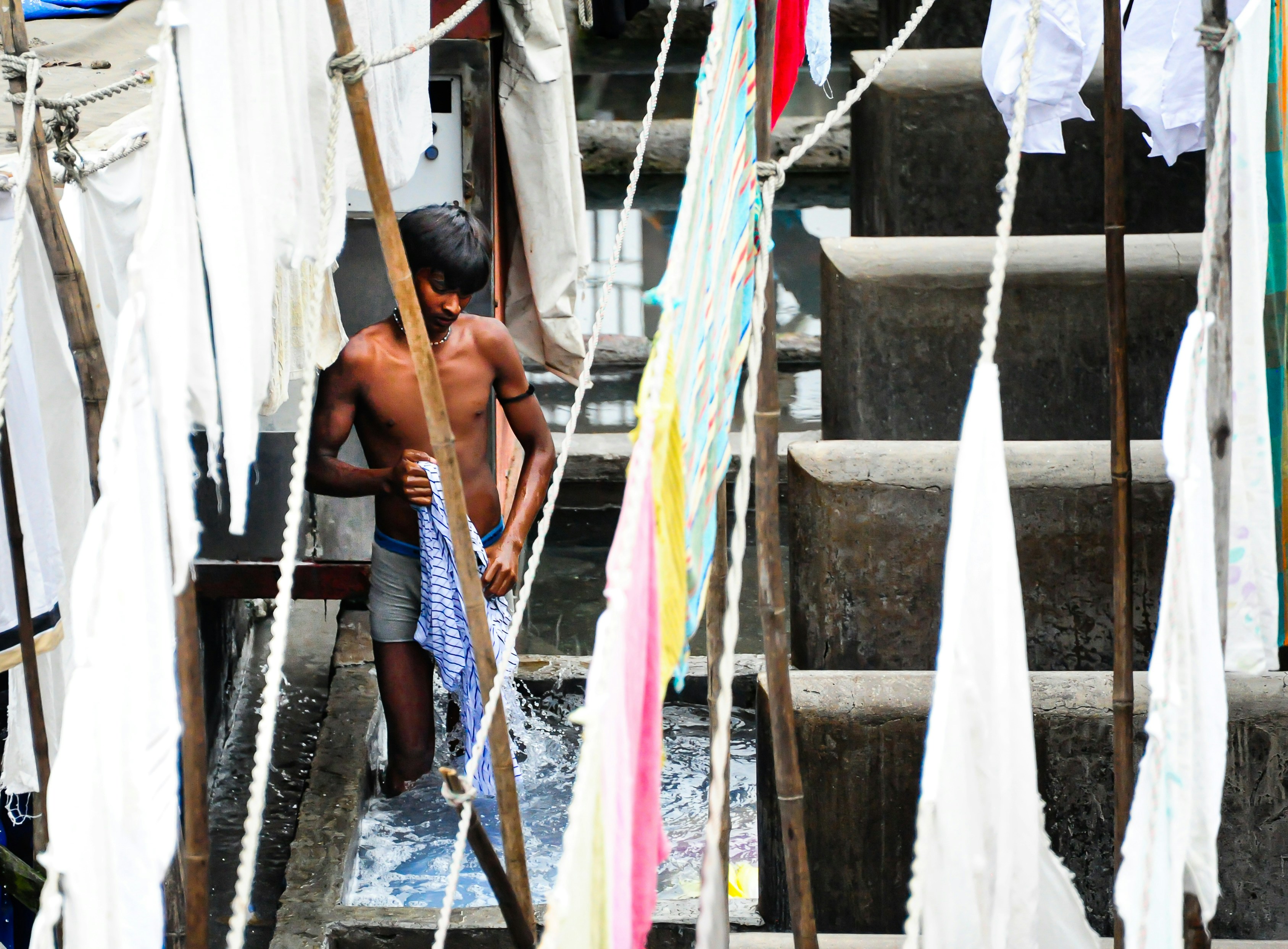 Young boy working at an outdoor laundry facility.