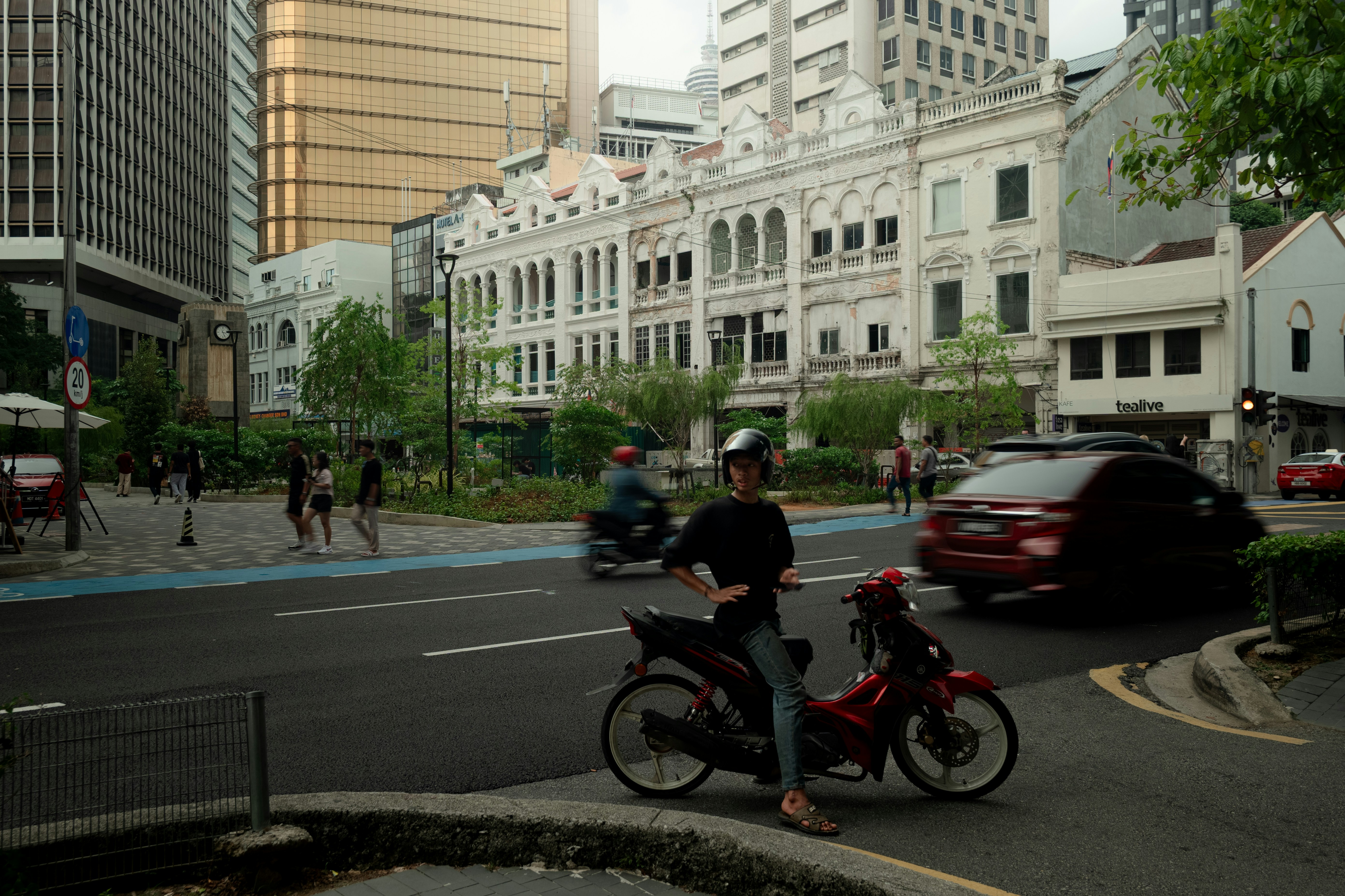 Un motocycliste attend à une intersection de la ville avec de vieux bâtiments.