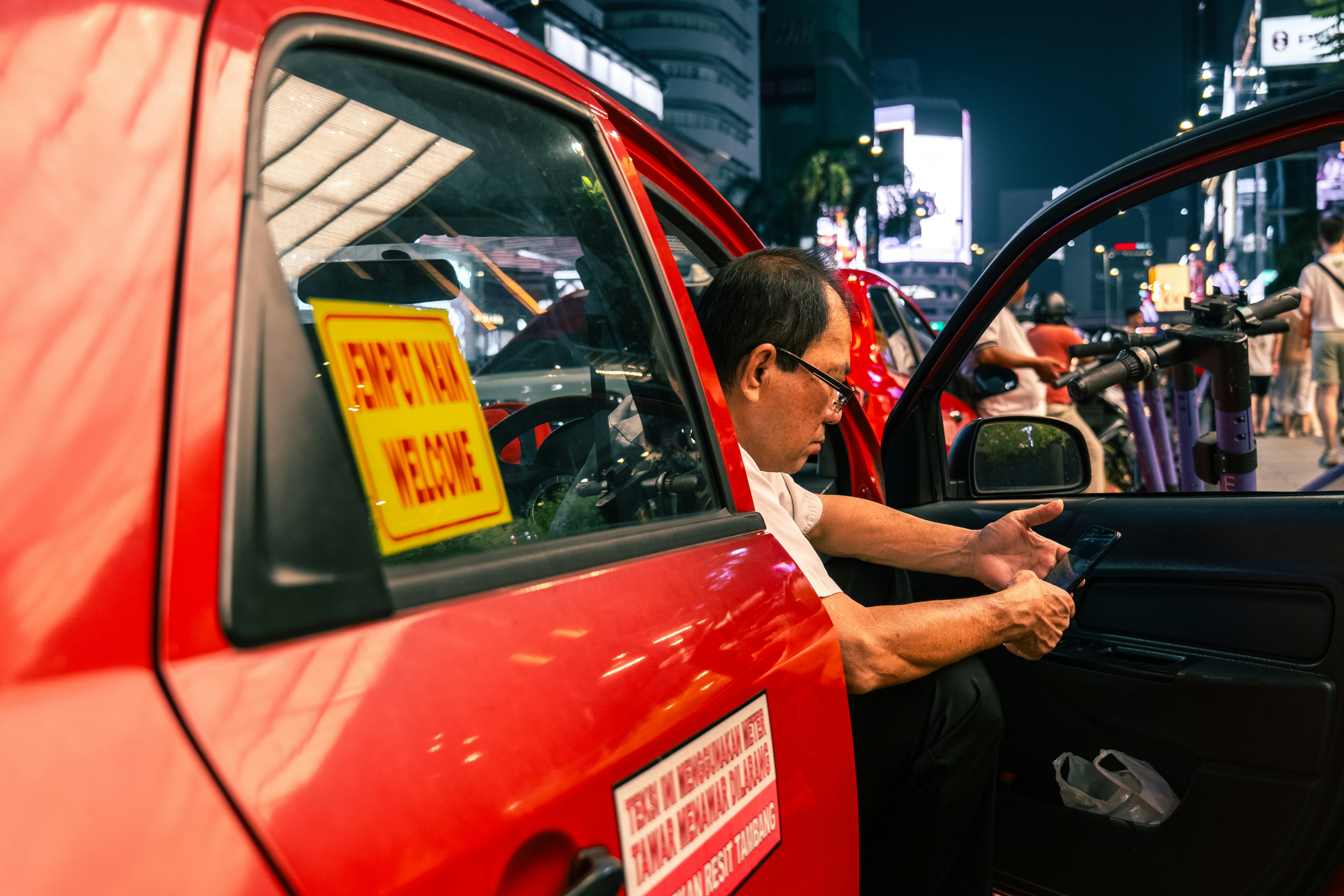 Homme entrant dans un taxi rouge la nuit