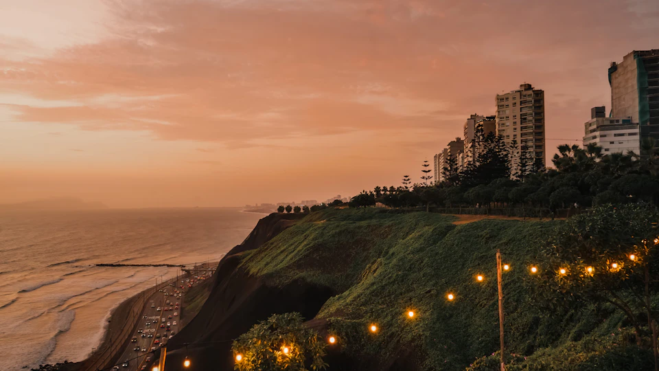 Serene coastal scene at sunset with cliff overlooking ocean and buildings in background