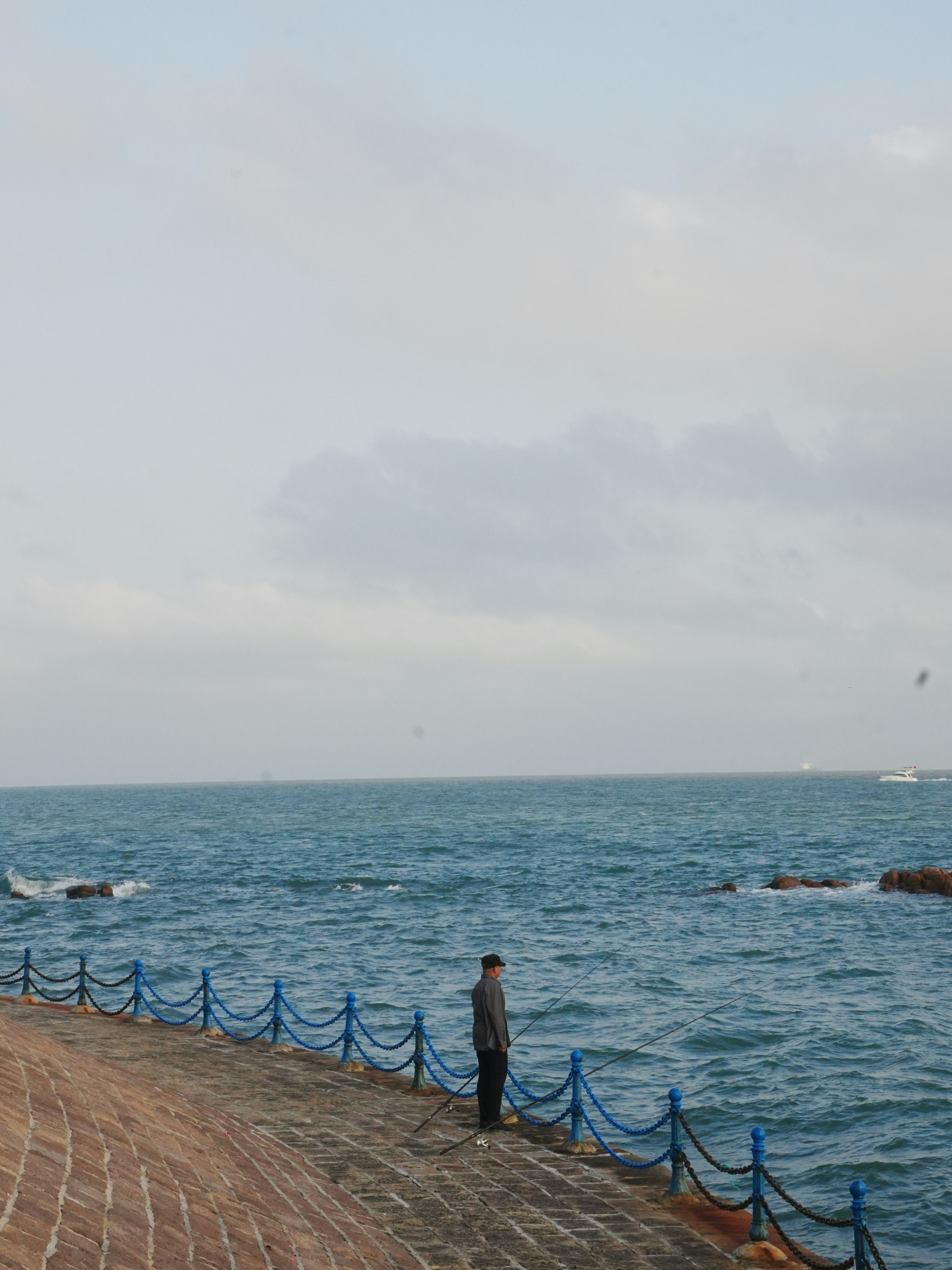 A person stands by the ocean on a cloudy day.