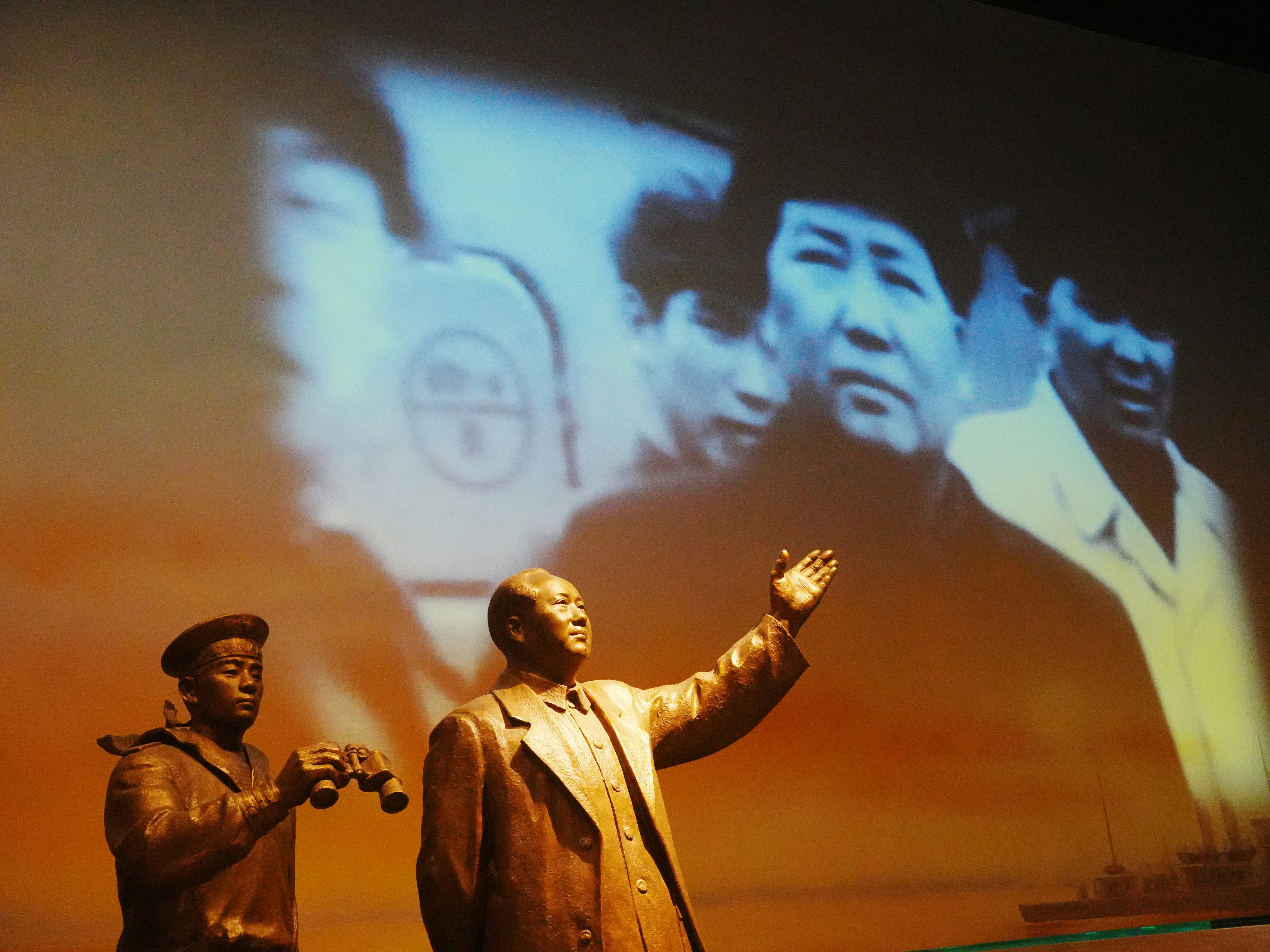 Statues of historical figures with projected images behind them.