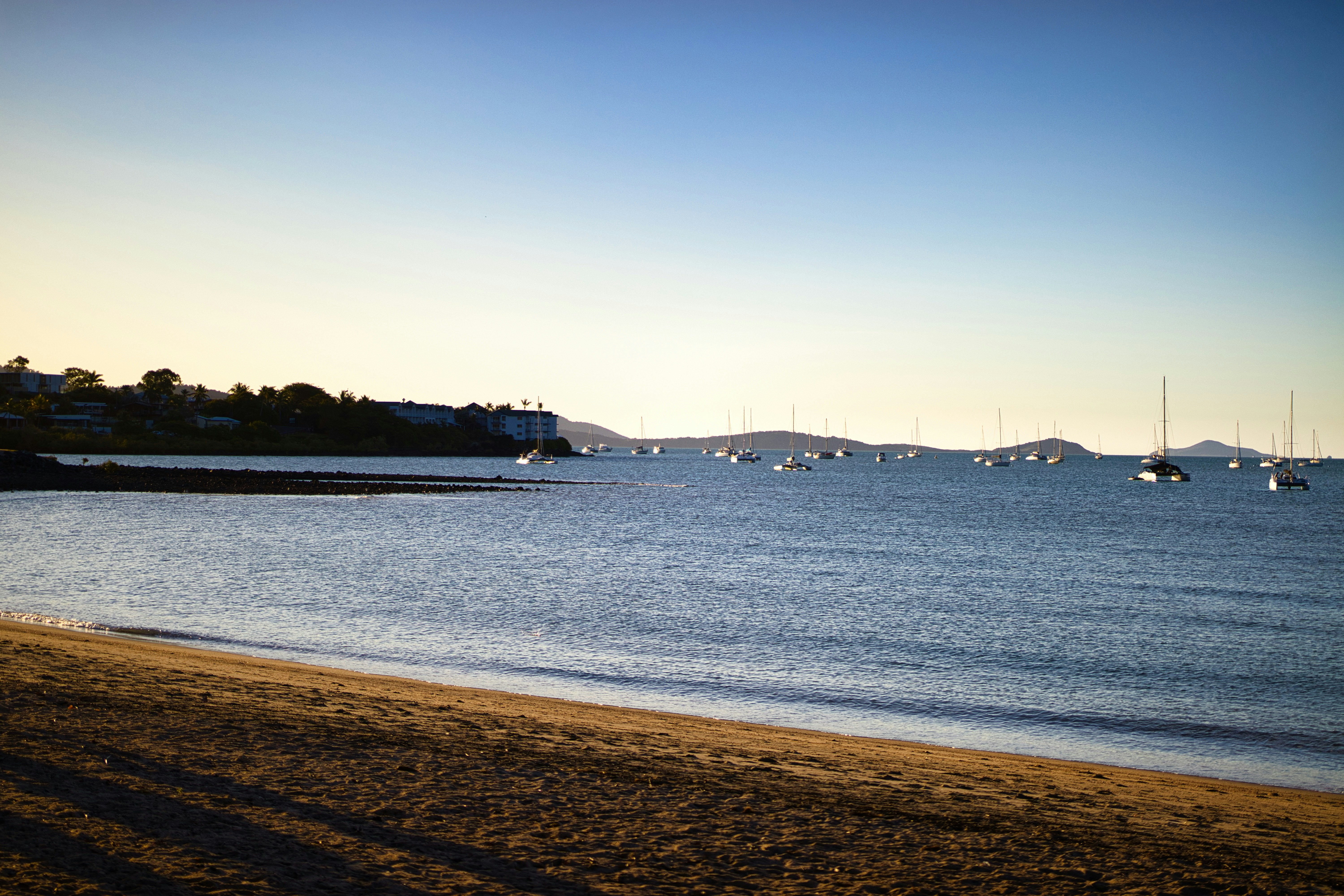Sailboats anchored in a calm bay at sunset