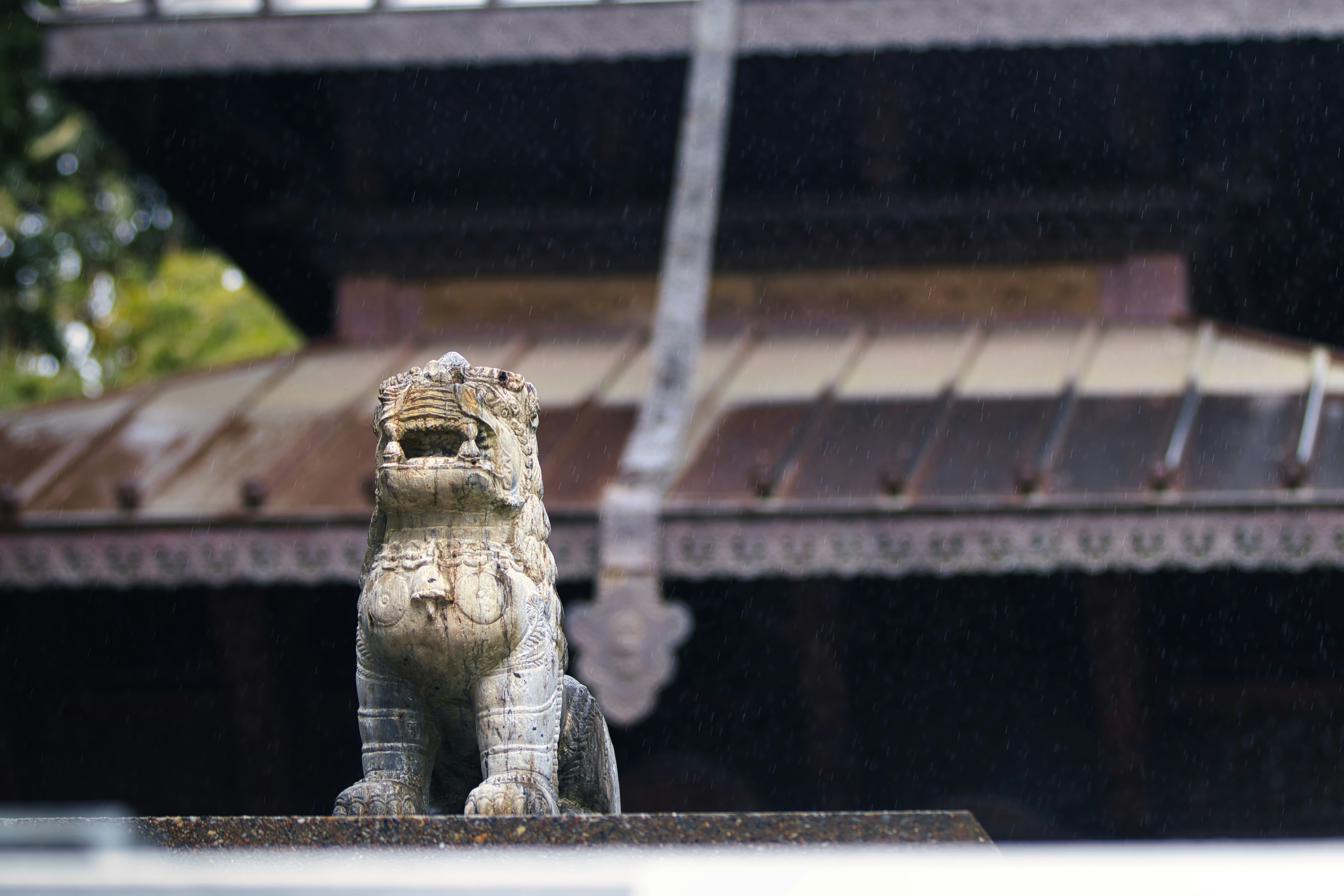 Stone lion statue in front of a temple roof