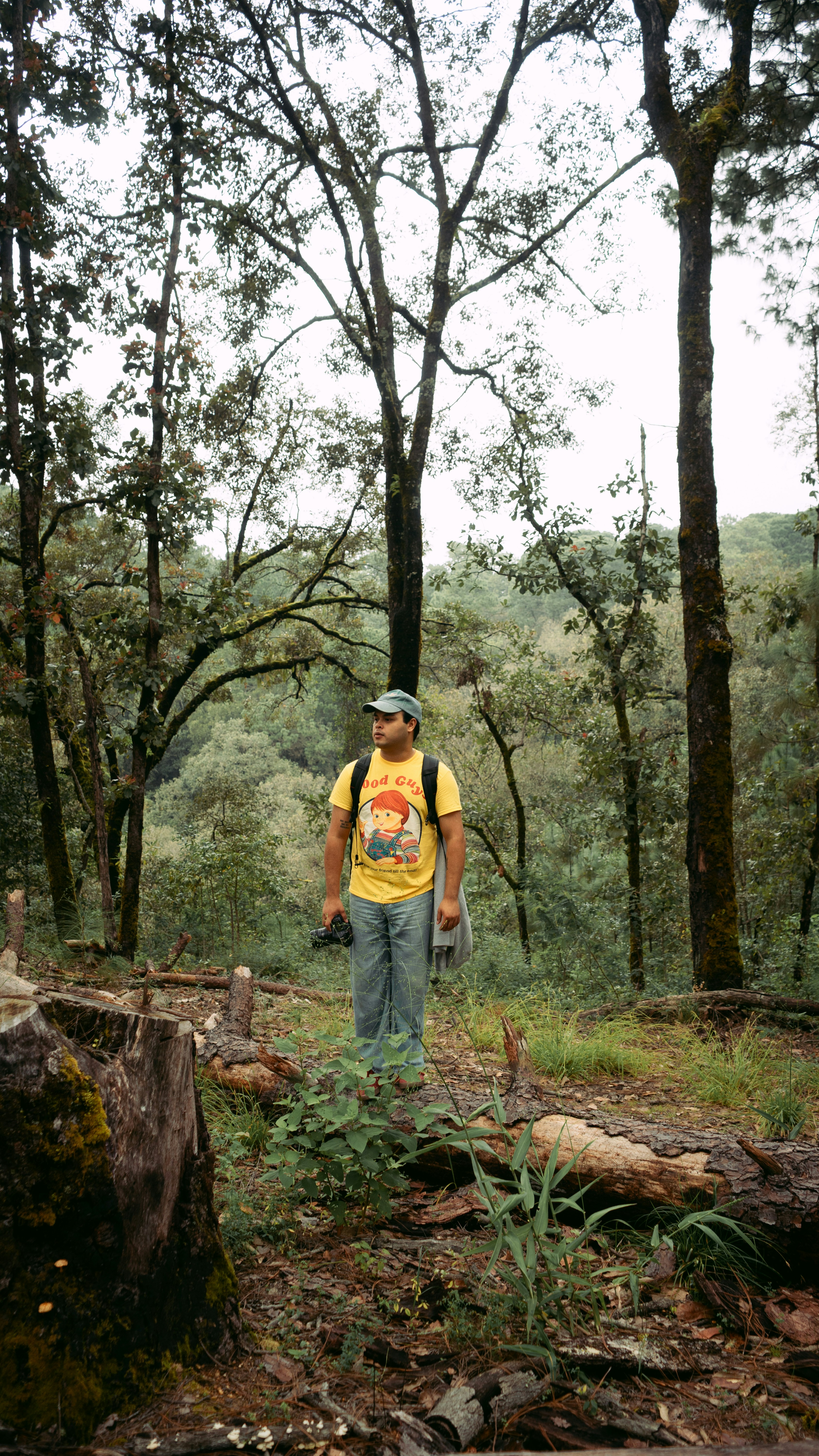 Man standing in a forest with trees and foliage.