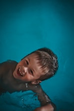 Boy smiling in blue swimming pool water