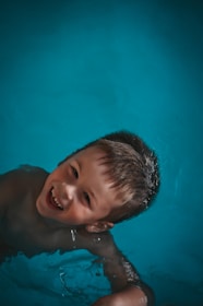 Boy smiling in blue swimming pool water