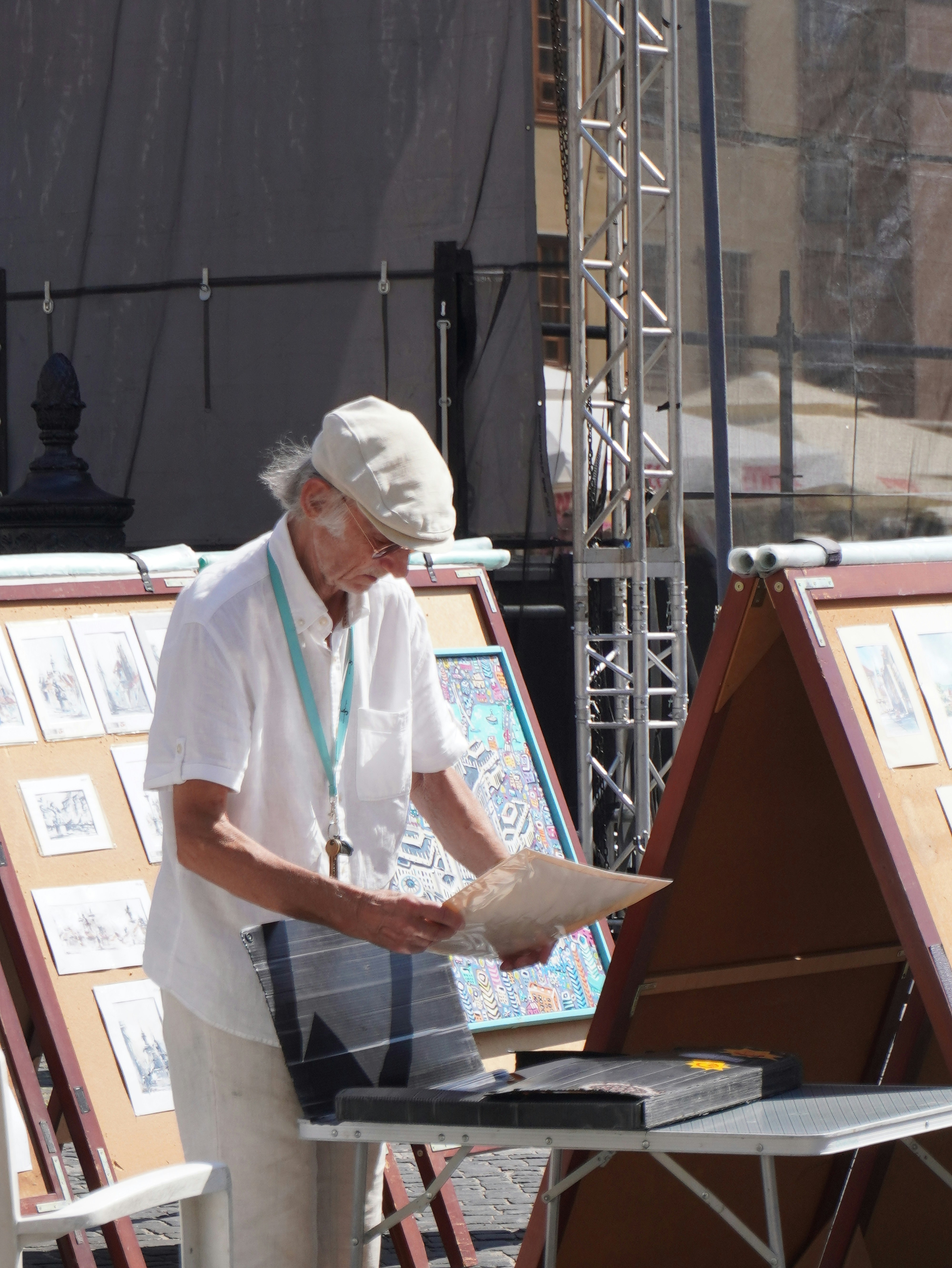 An artist examines his work displayed on easels.