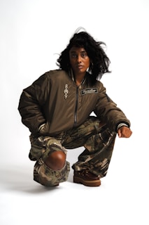 Woman in bomber jacket and camouflage pants crouching