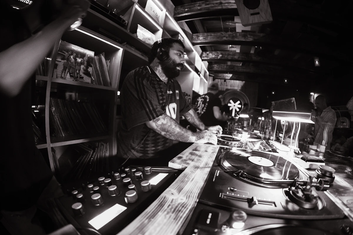 A DJ performs at turntables in a dark club