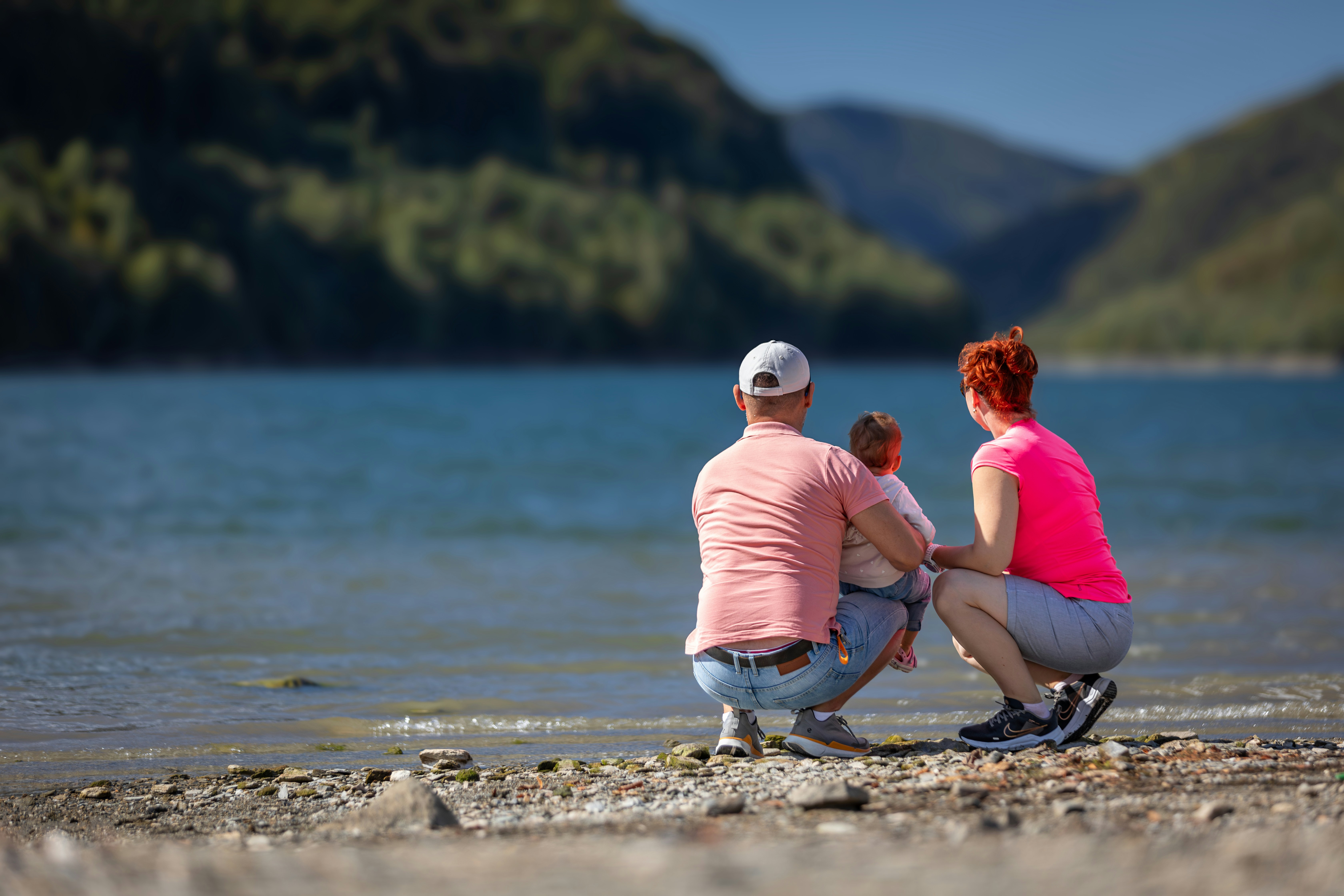 Familie mit Blick auf einen ruhigen See mit Bergen