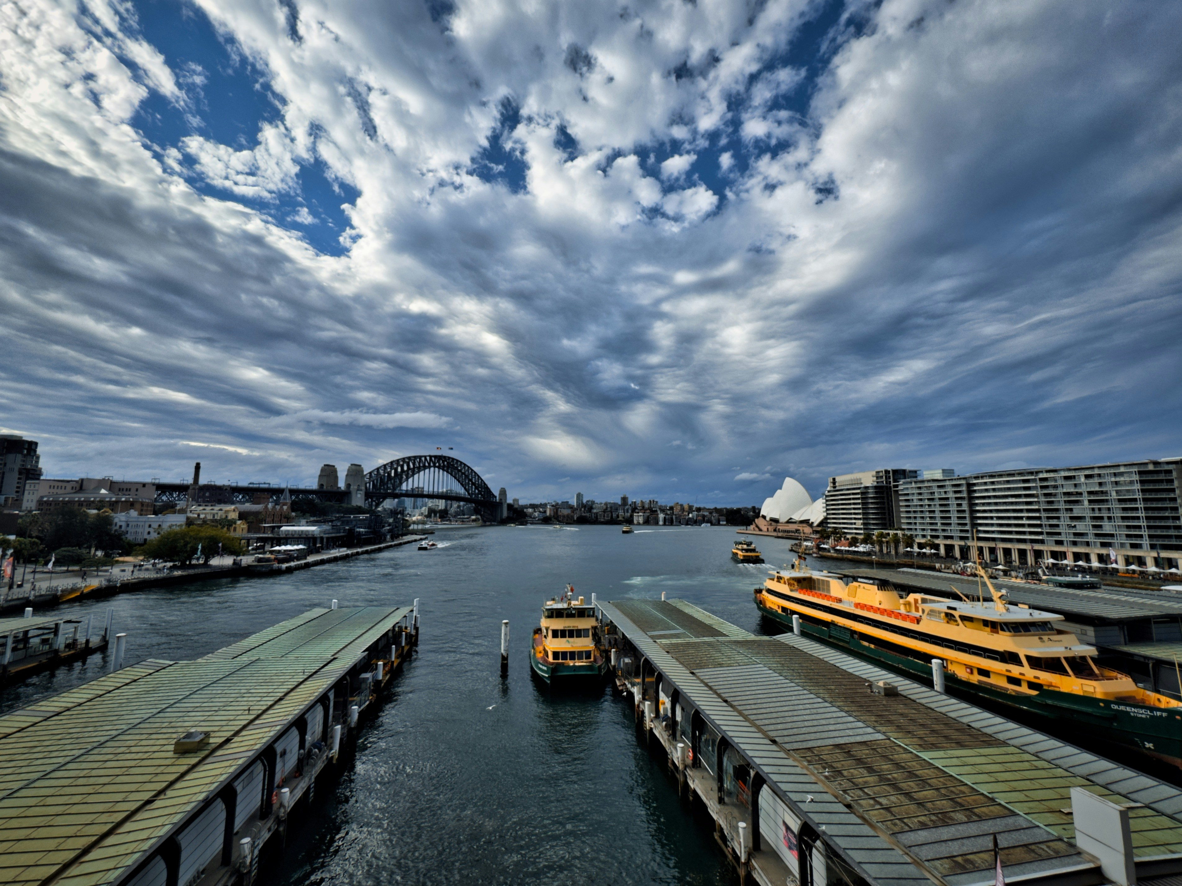 Ferries docked at a harbor with sydney harbor bridge.