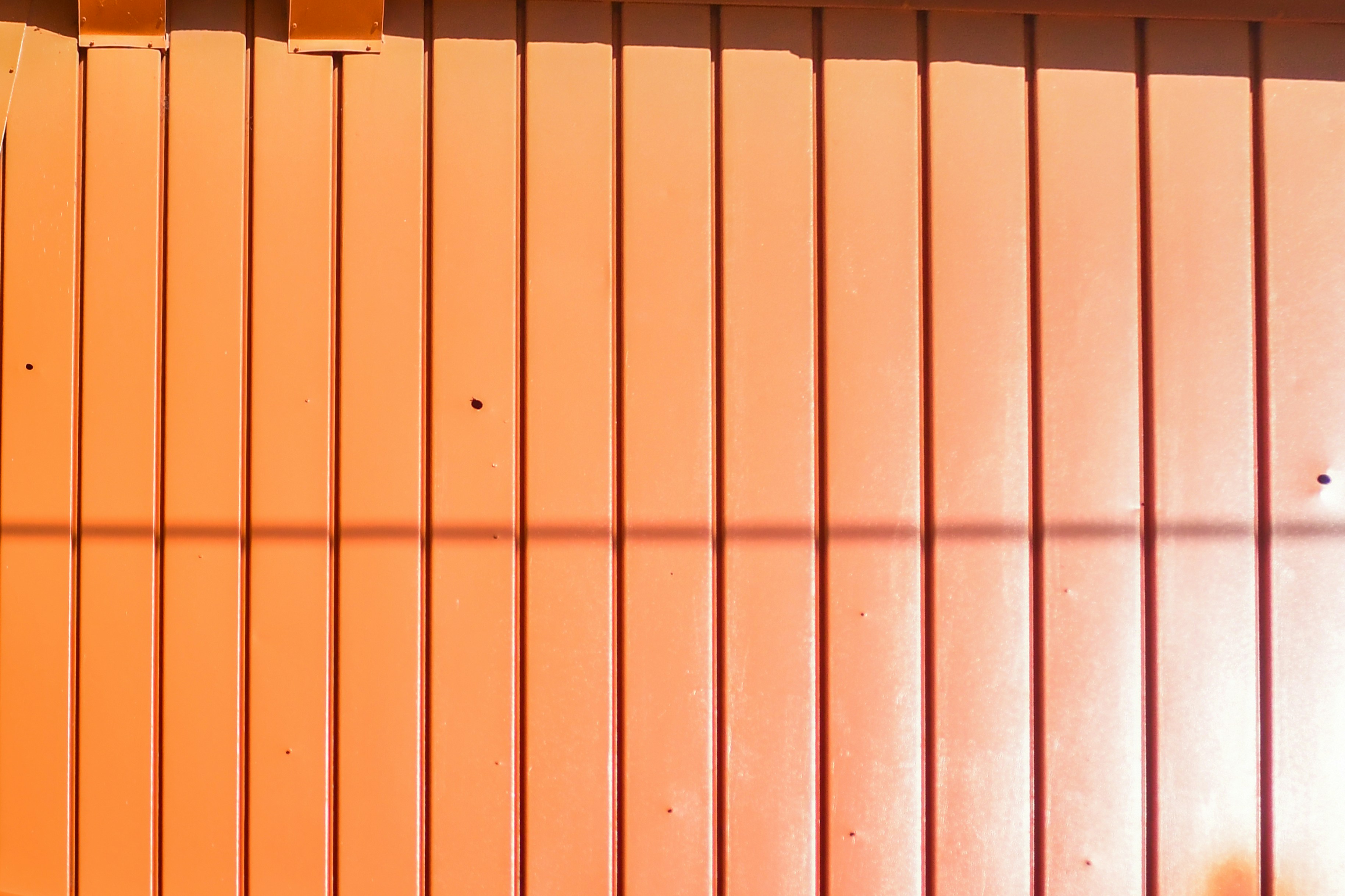 Orange corrugated metal wall with shadows
