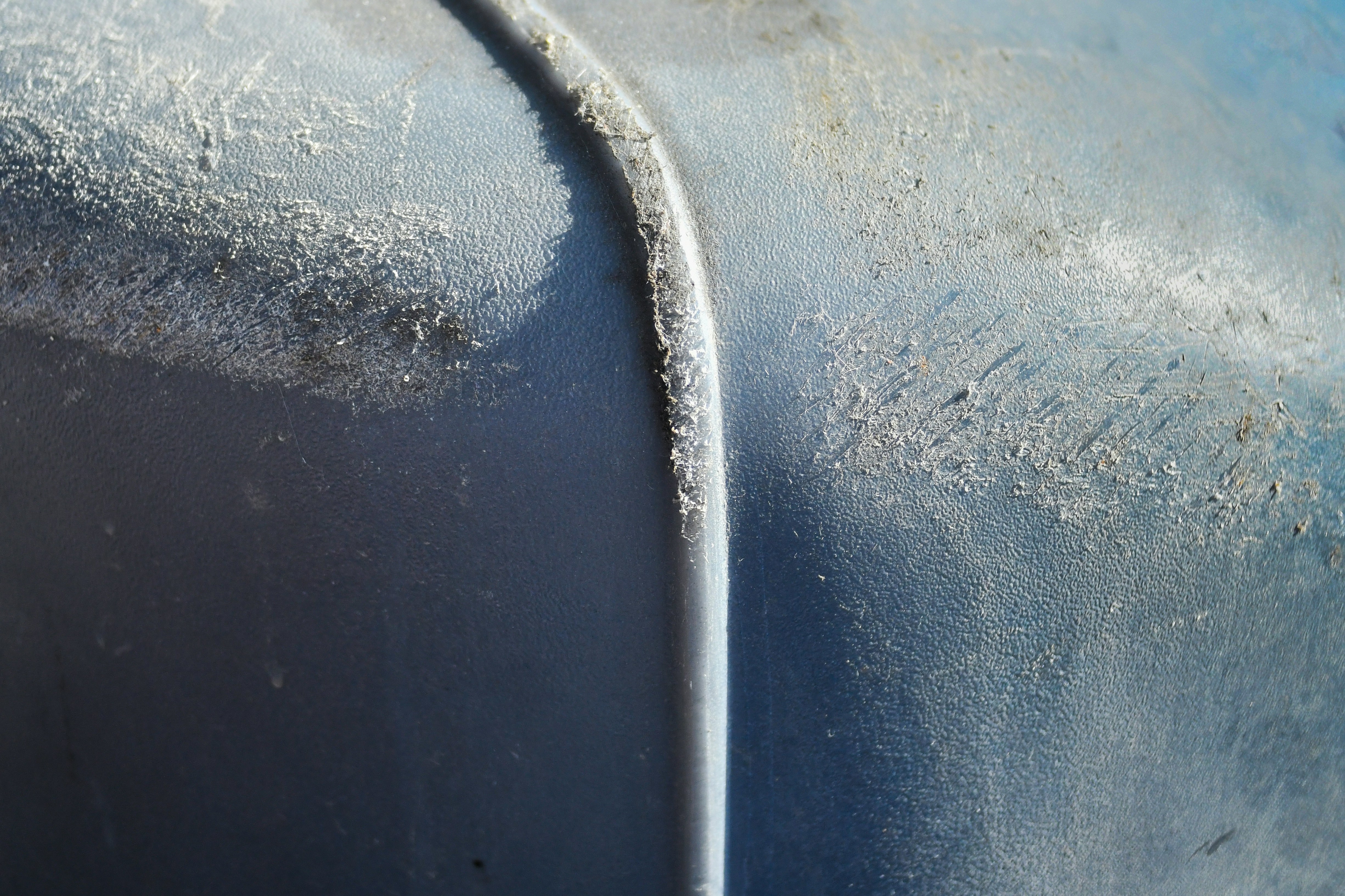 Close-up of a weathered blue surface with a seam.