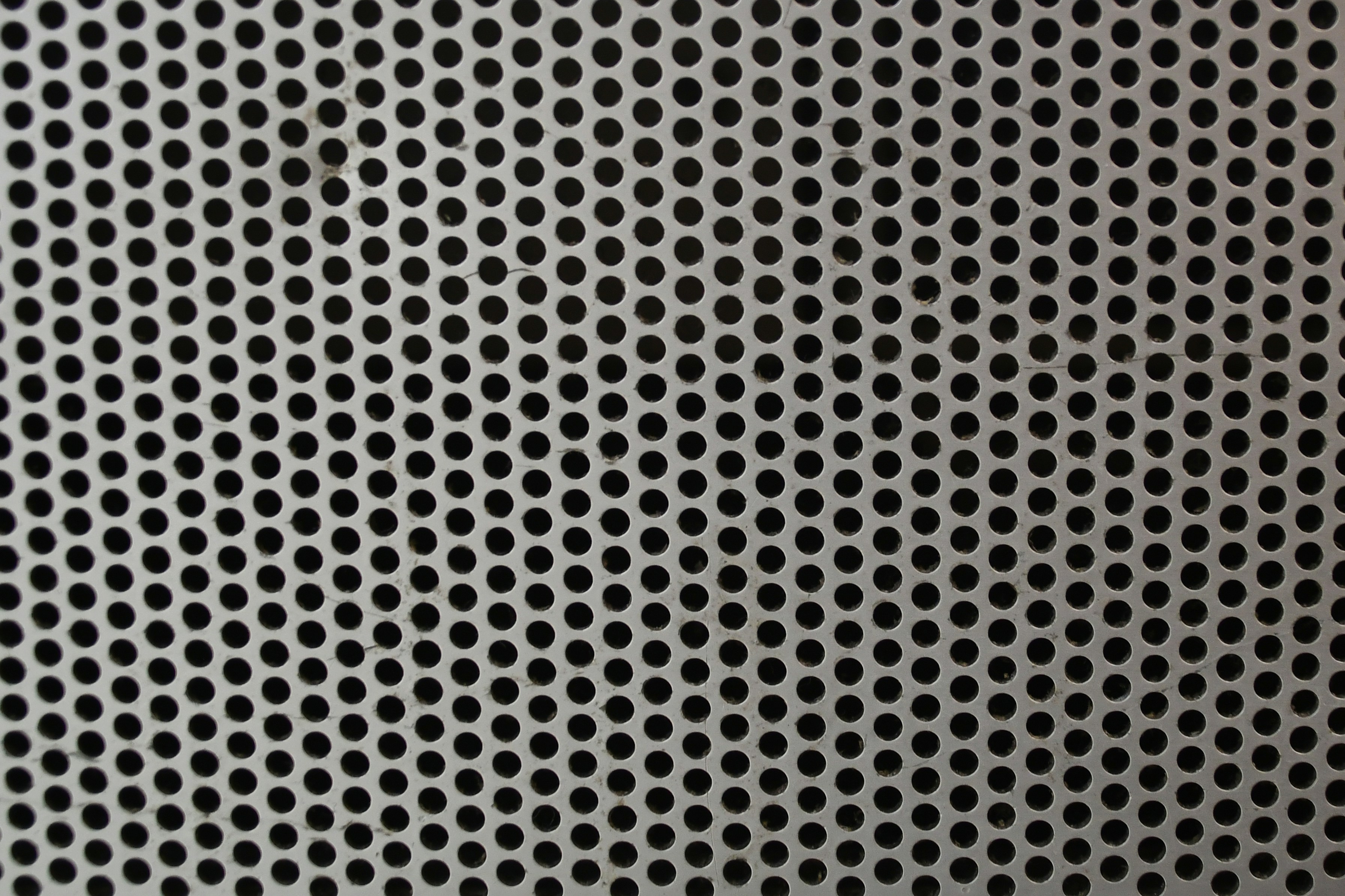 Perforated metal surface with uniform circular holes.