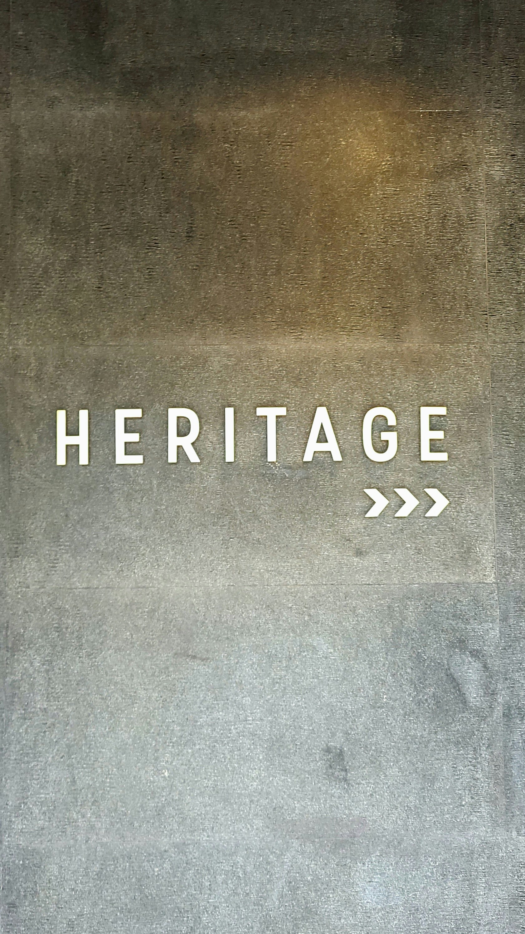 White text "heritage" with arrow on textured background