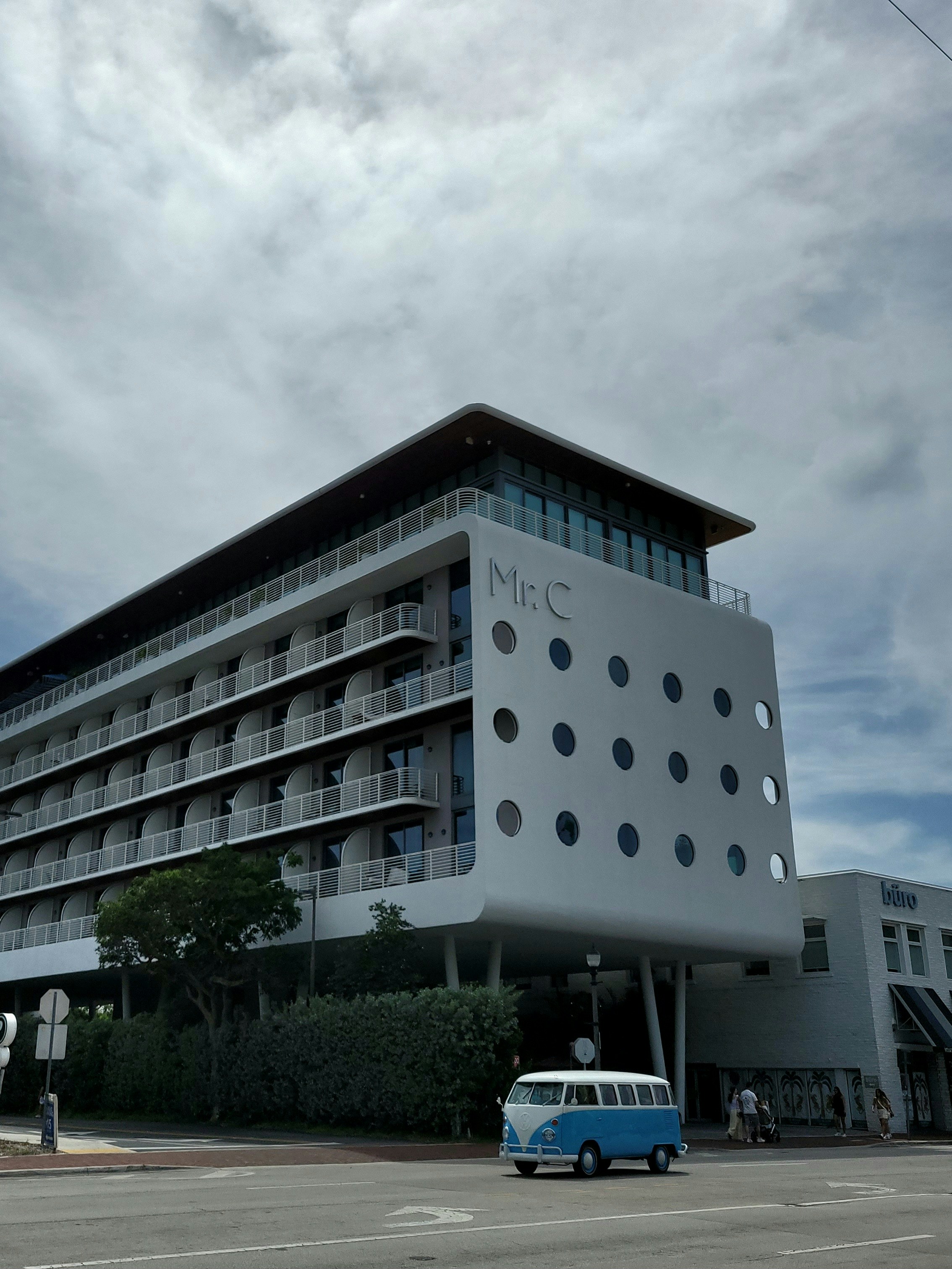Modern hotel building with blue van on street.
