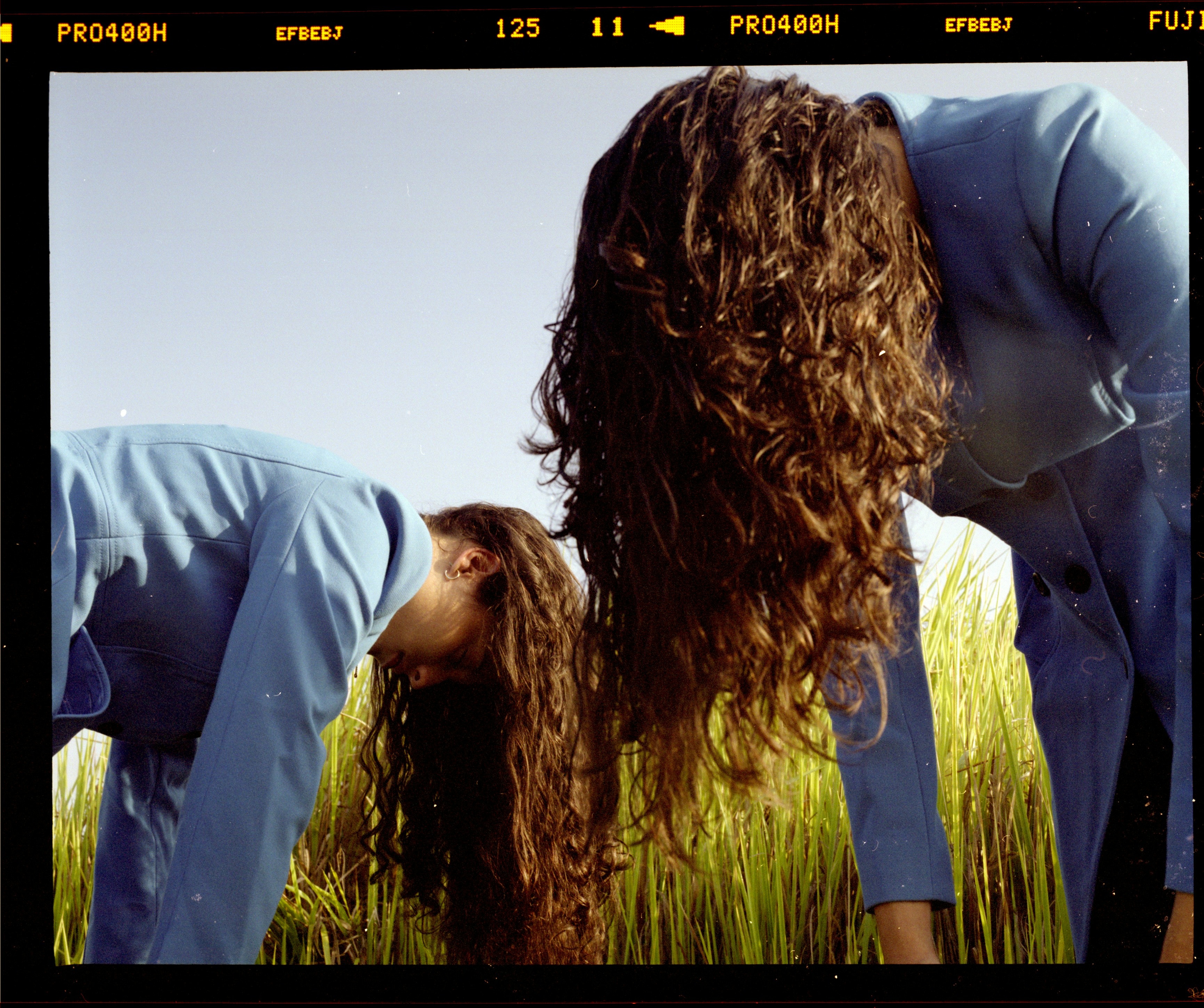 Zwei Frauen mit langen lockigen Haaren, die sich nach unten beugen