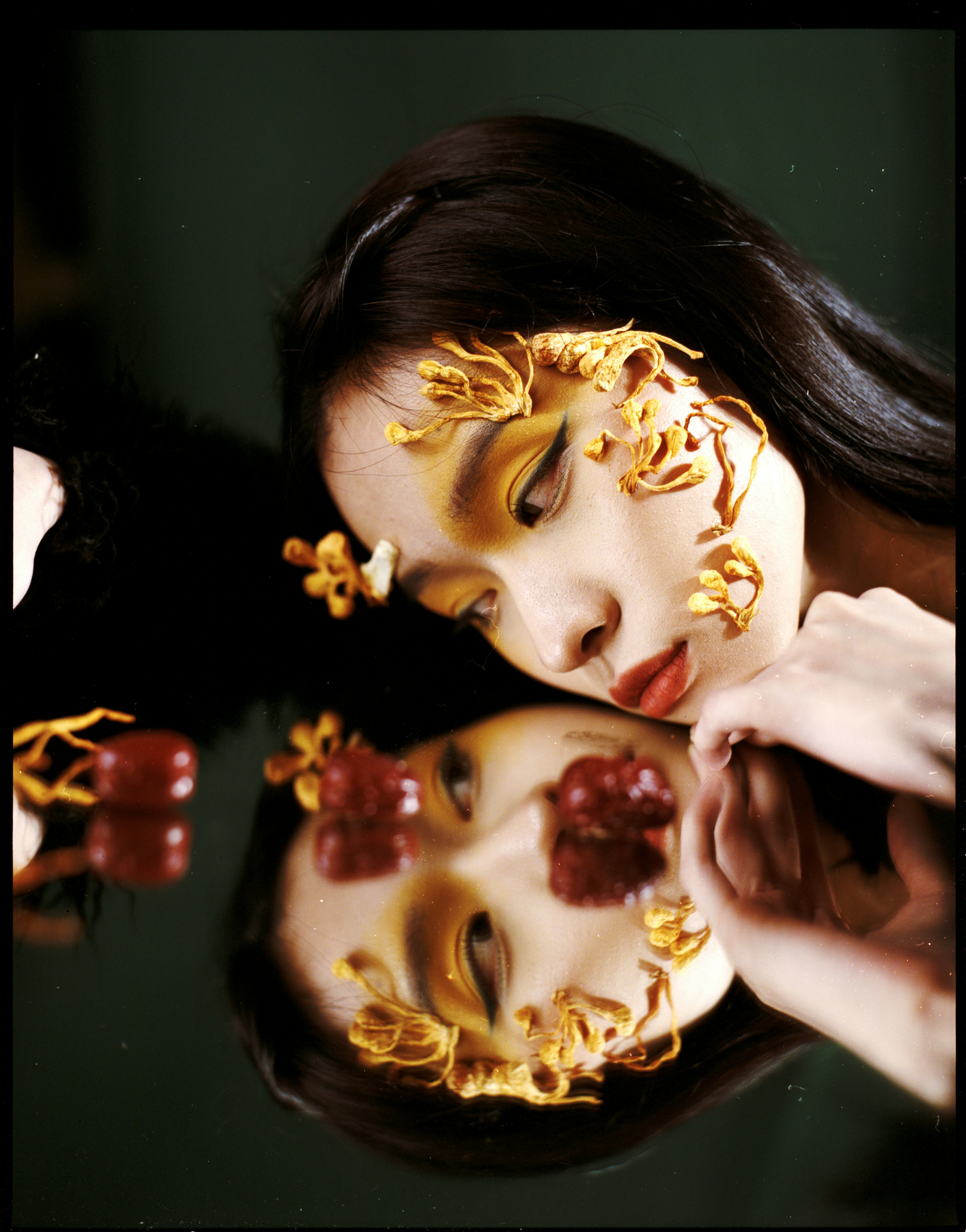 Woman with artistic makeup and floral accents reflected