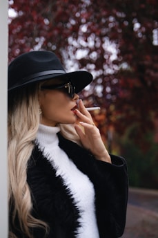 Woman in hat and sunglasses smoking a cigarette