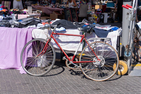 Red bicycle parked by a market stall