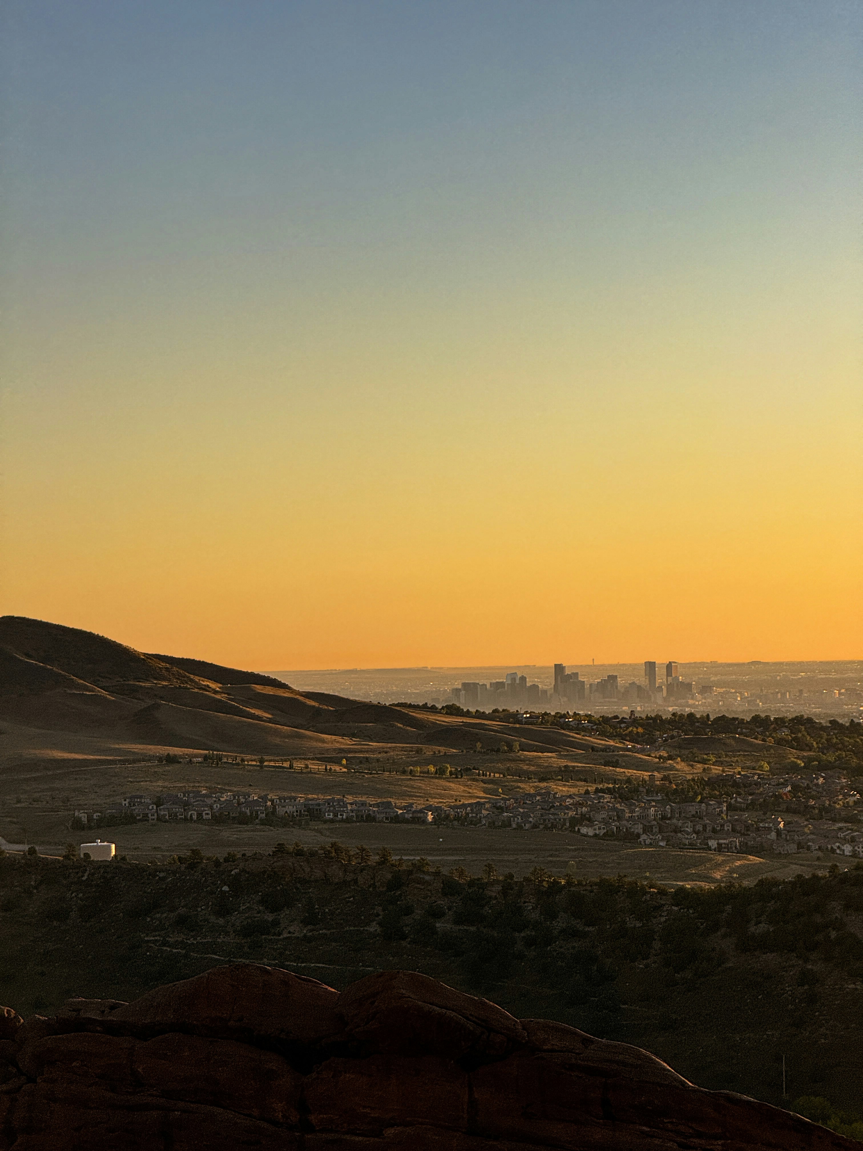 City skyline visible at sunset over rolling hills