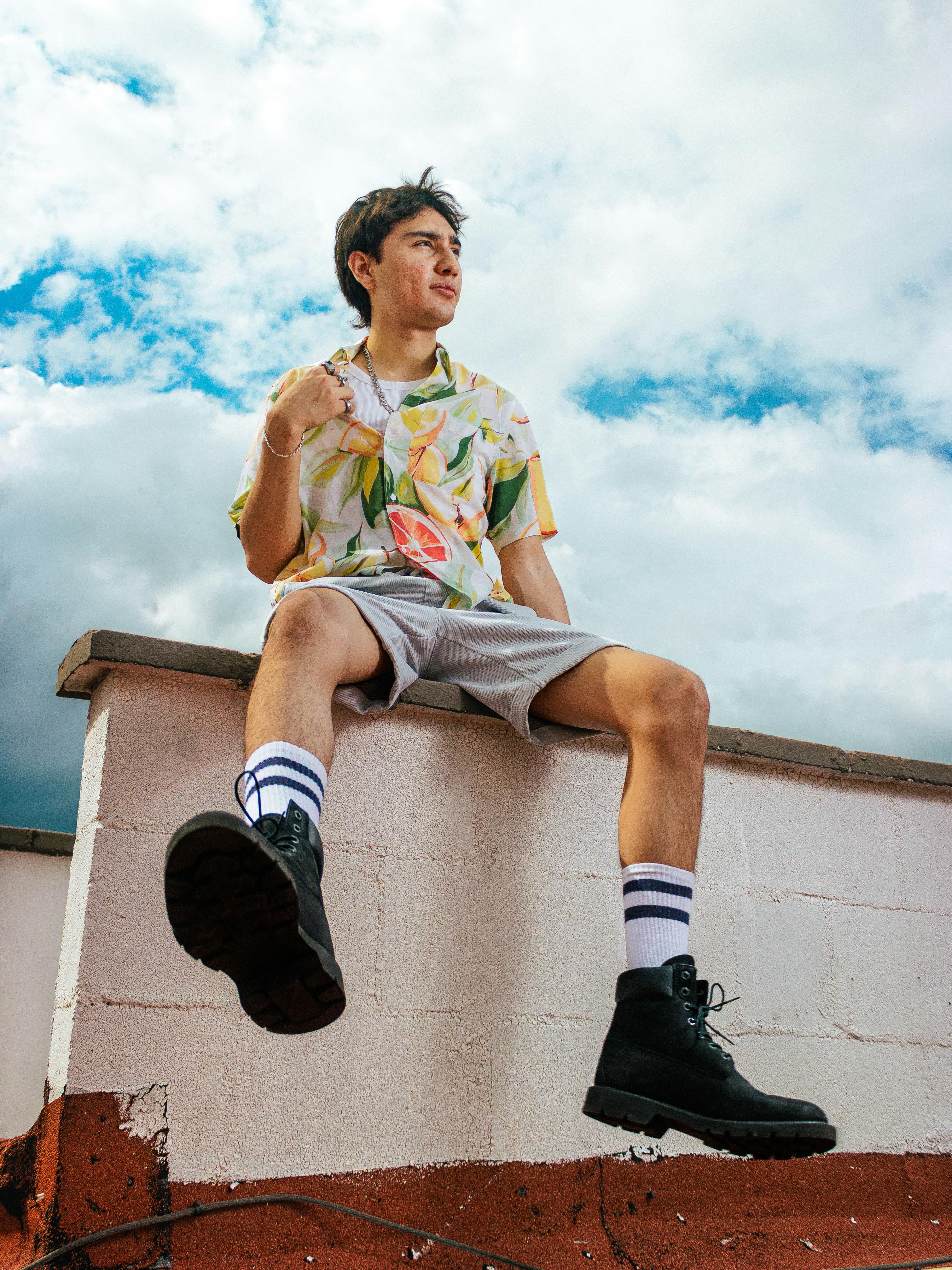 Young man in summer clothes sitting on a wall.