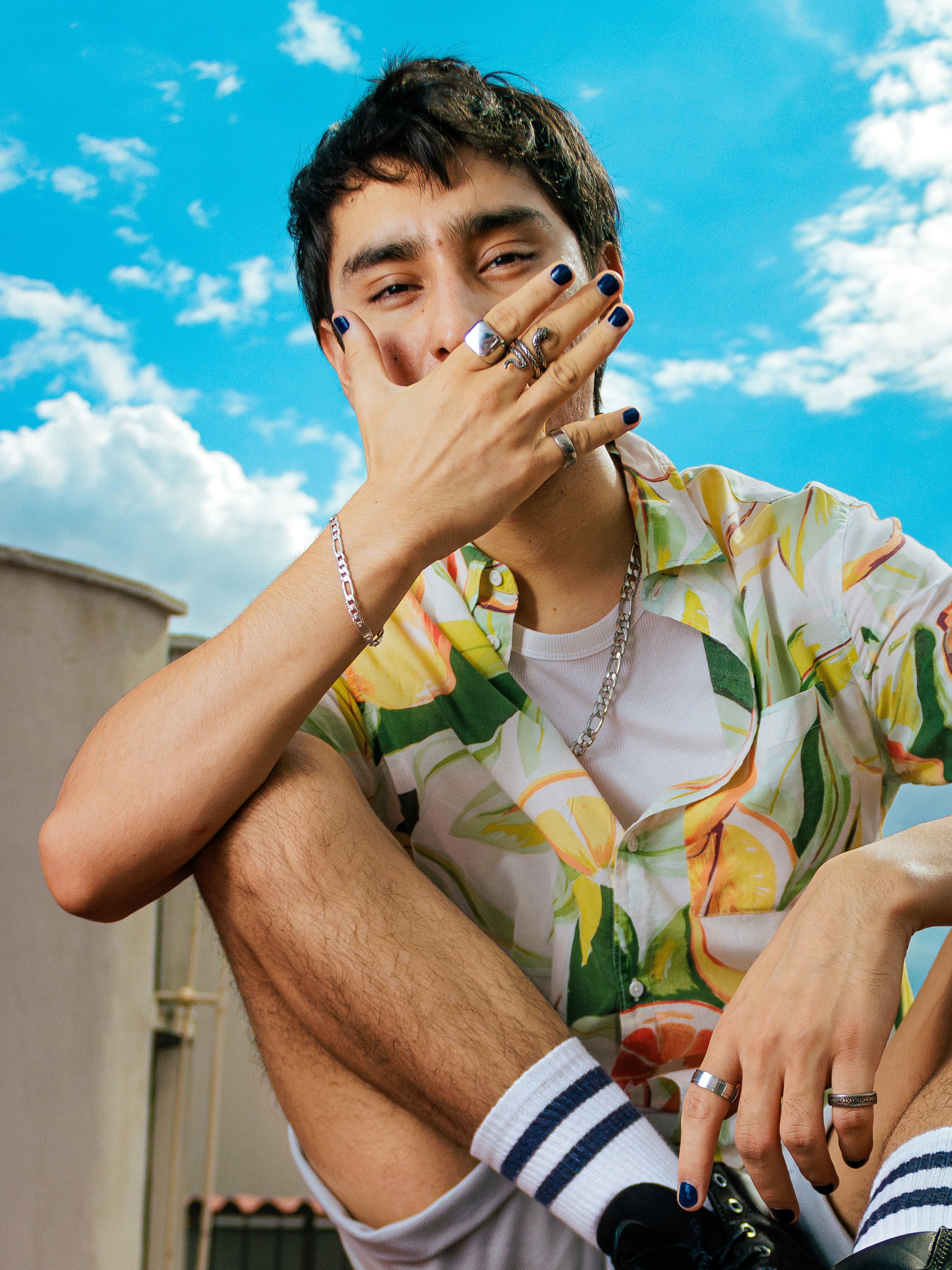 Young man with rings and nail polish on hand.