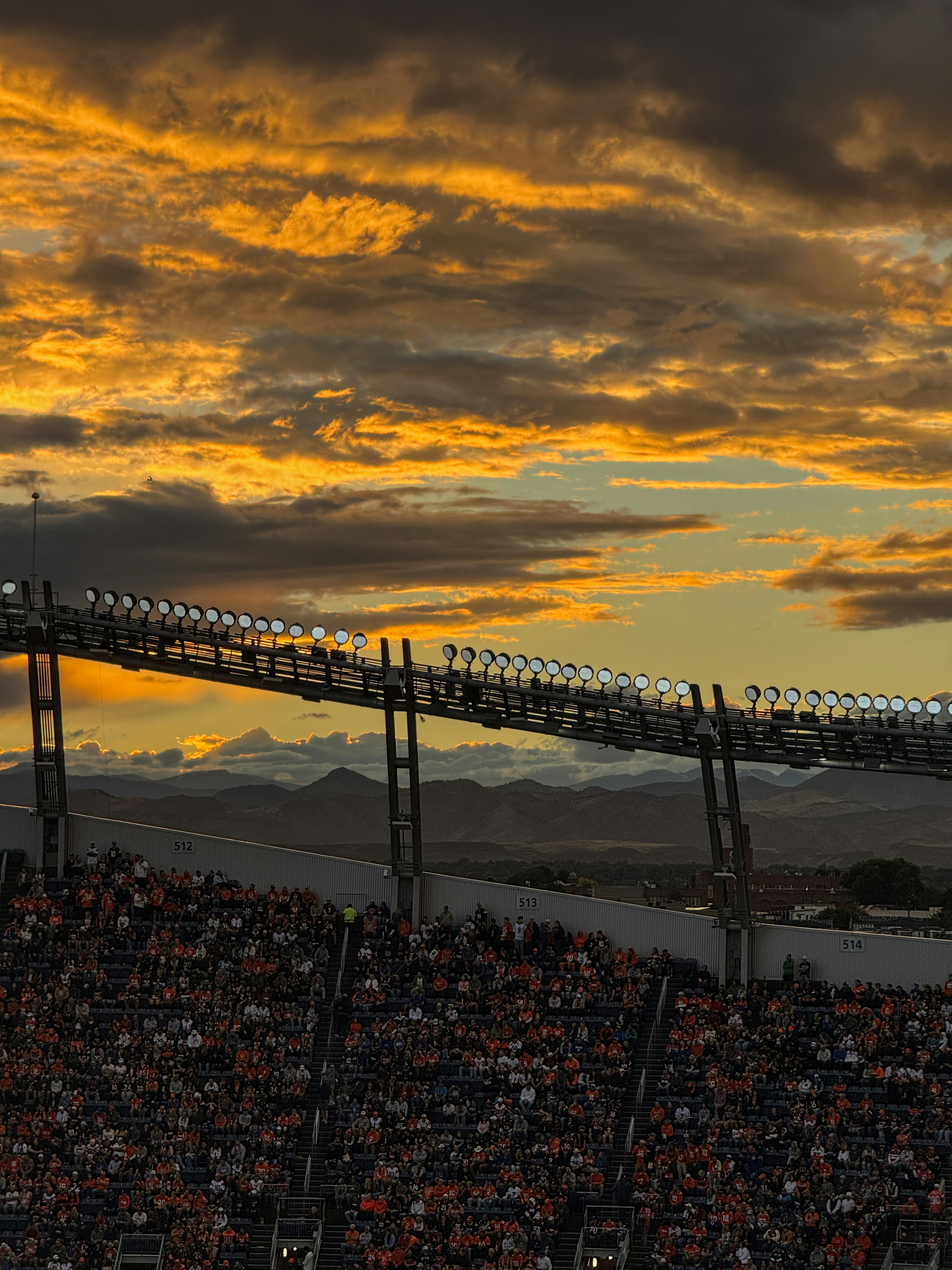 Stadium lights against a dramatic sunset sky