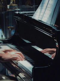 Hands playing a grand piano with sheet music