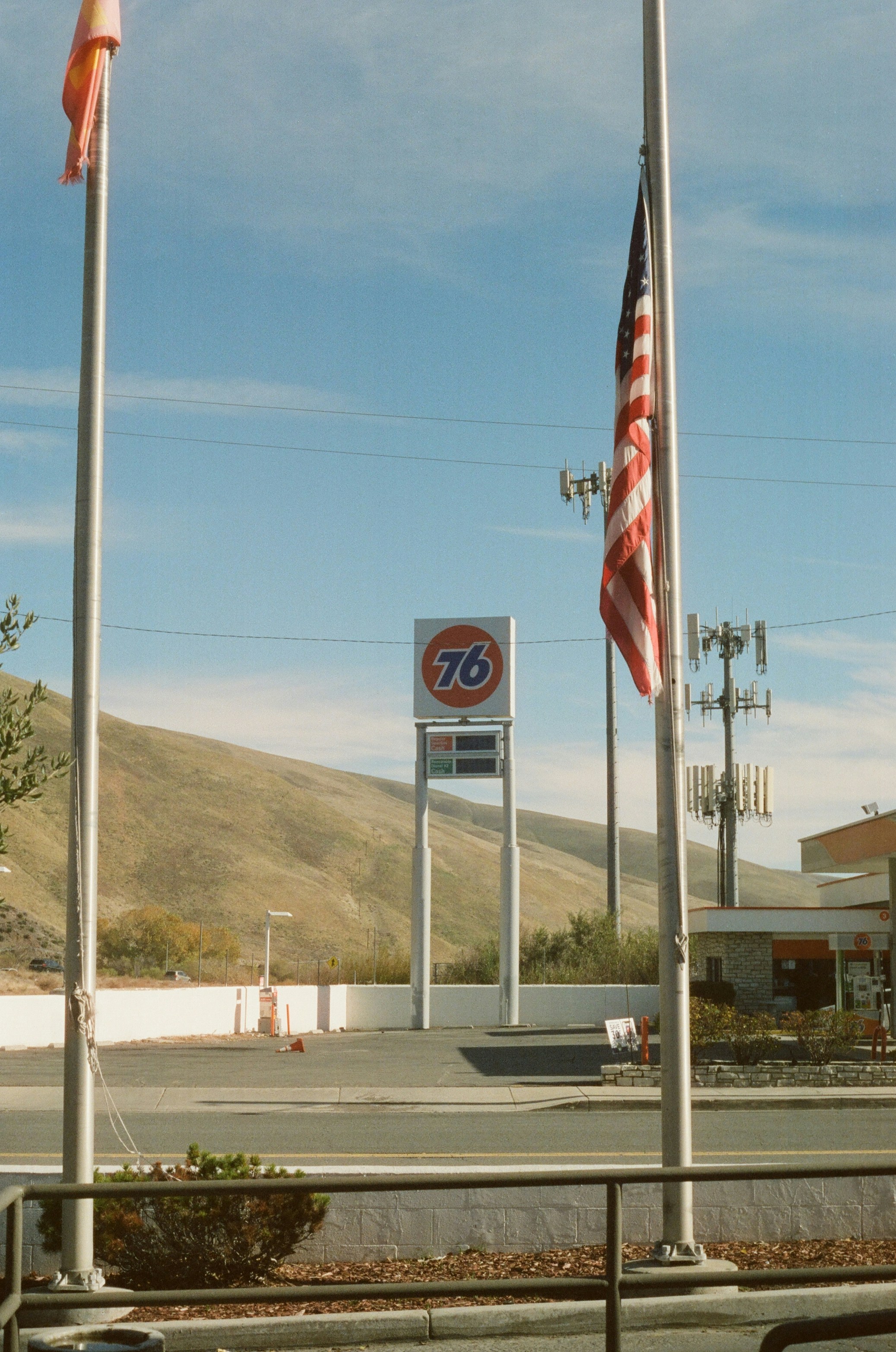 76 tanda pompa bensin dengan bendera Amerika berkibar.