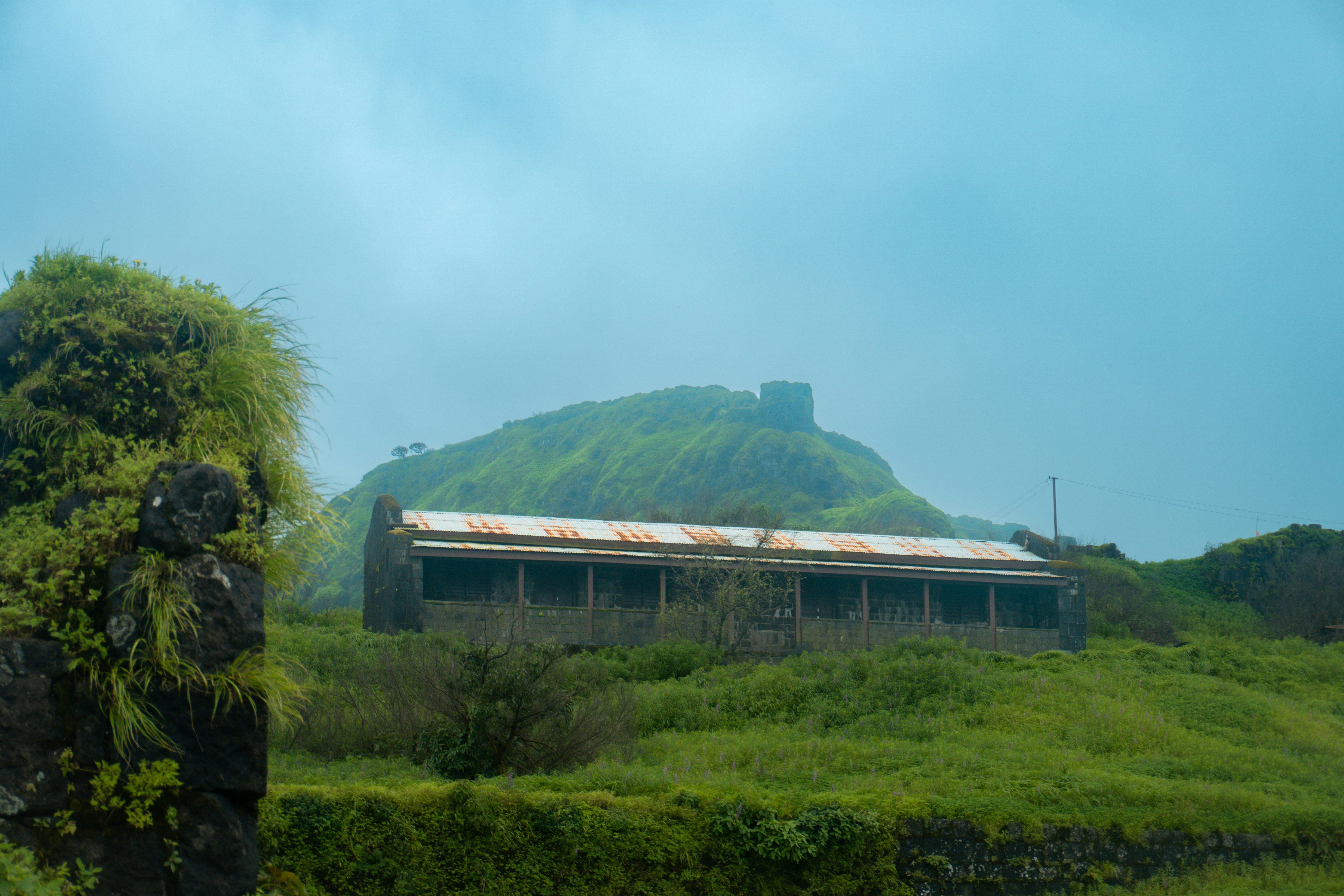 Ruined building on a grassy hill with fort ruins.
