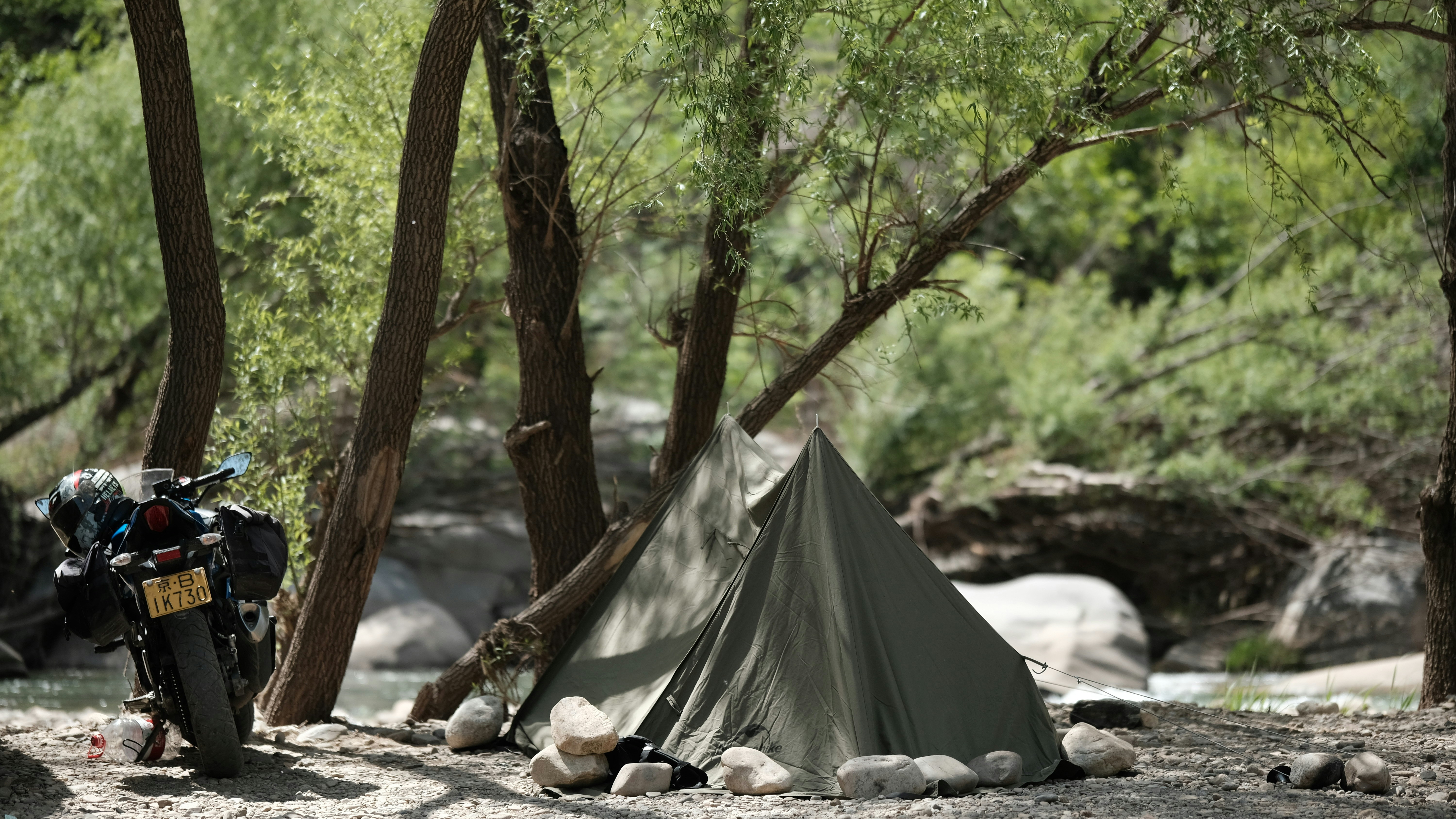 Tent and motorcycle parked by a stream