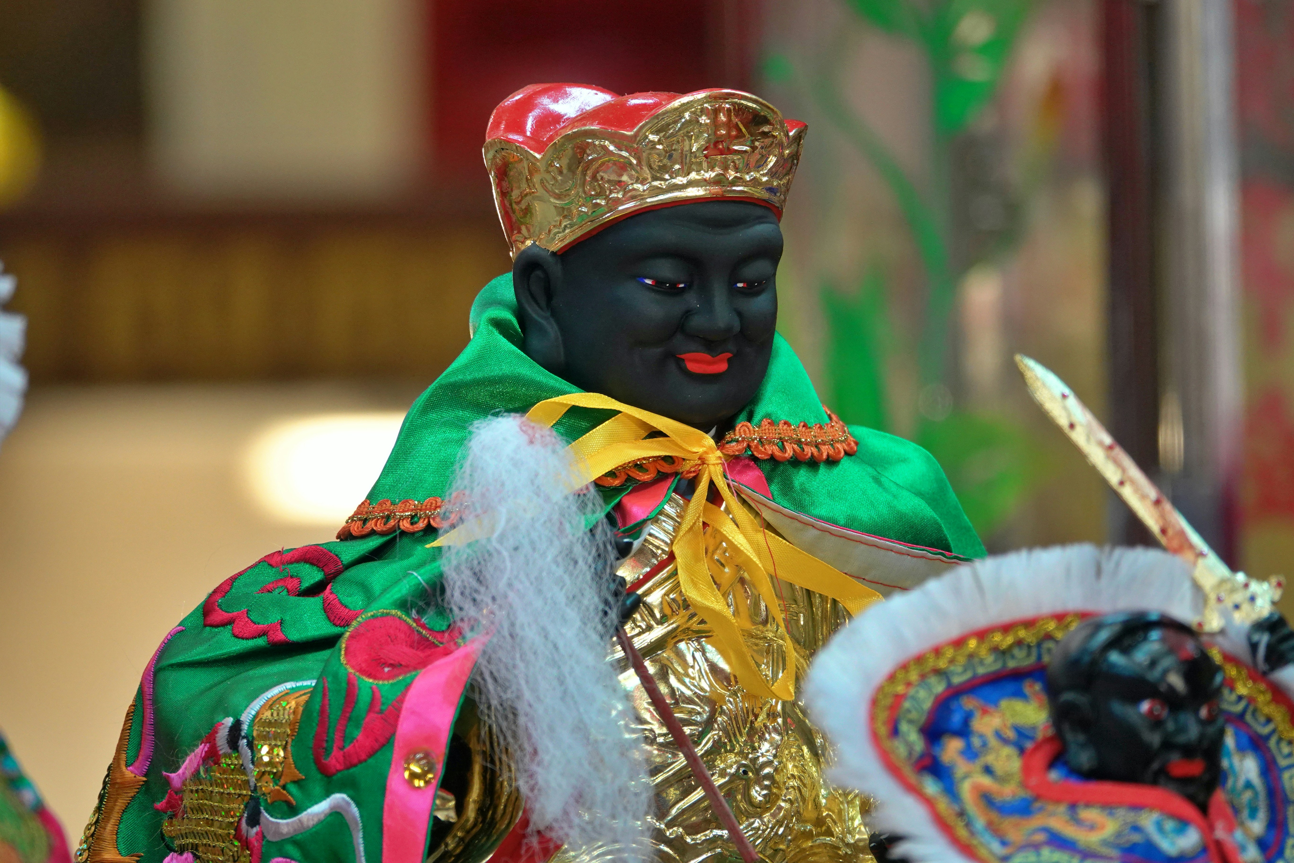 A dark-faced statue with a crown and green robe.