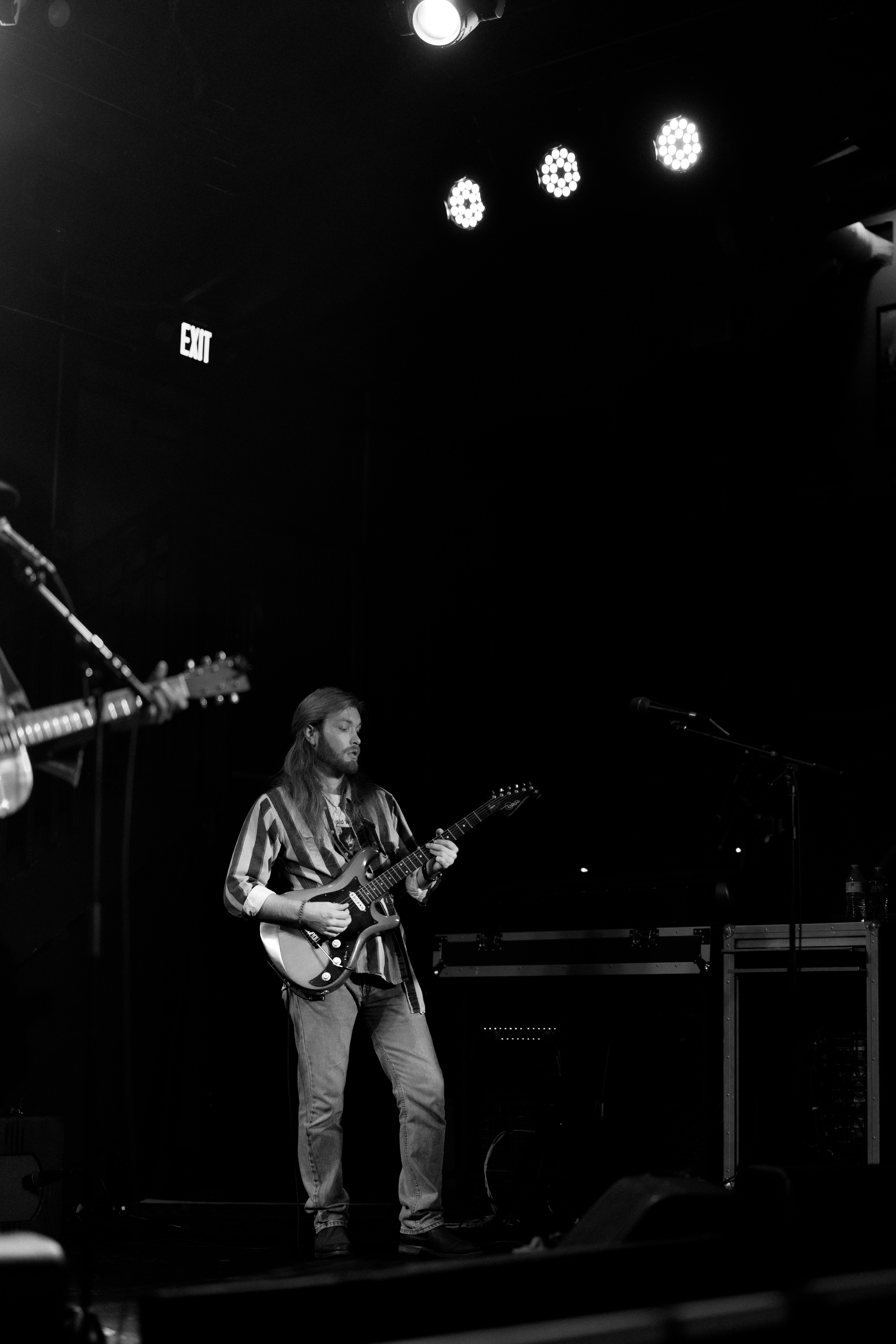 Musician playing guitar on a dimly lit stage.