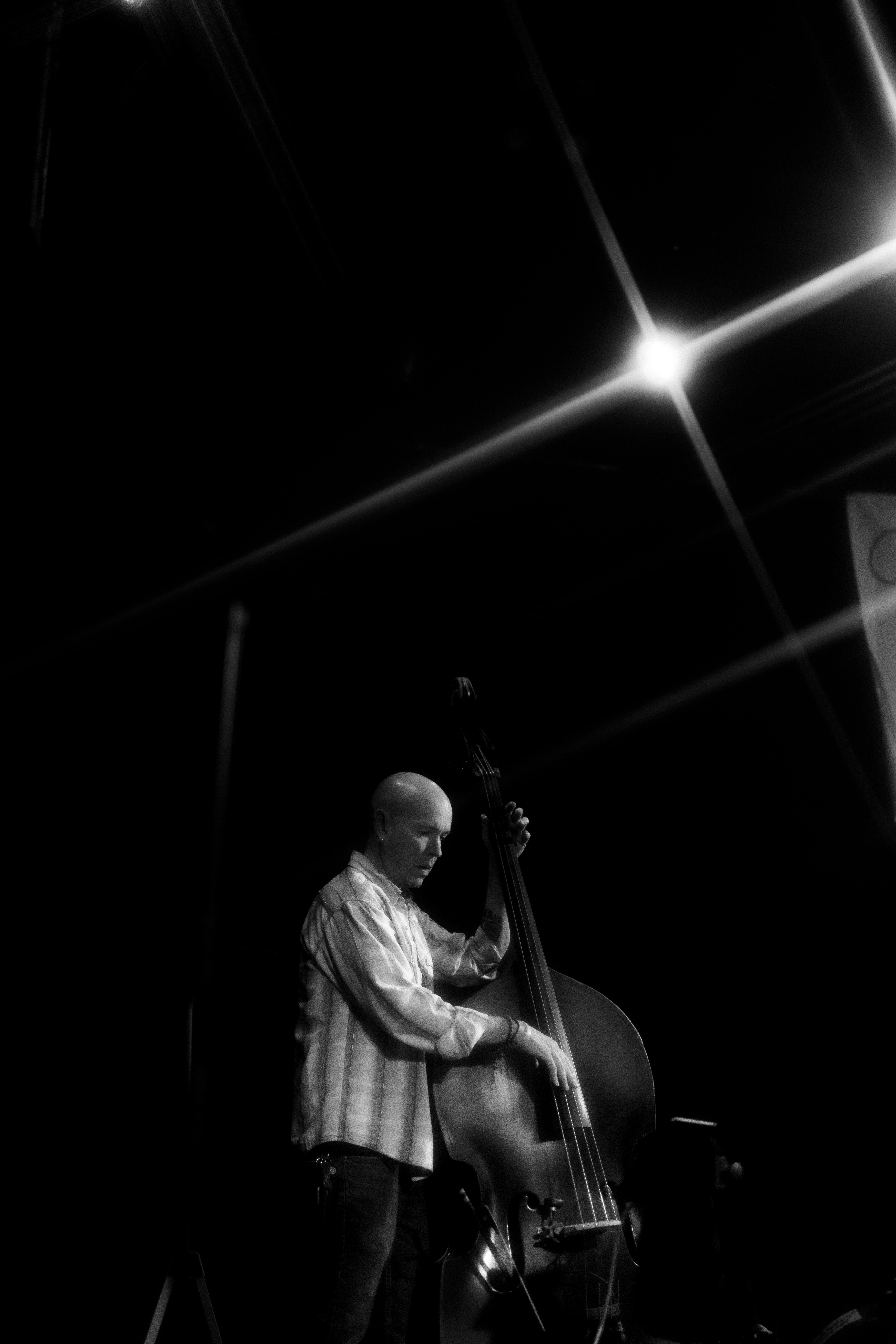 Man playing a double bass on a dark stage.