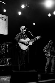 Musician plays guitar and sings on stage.