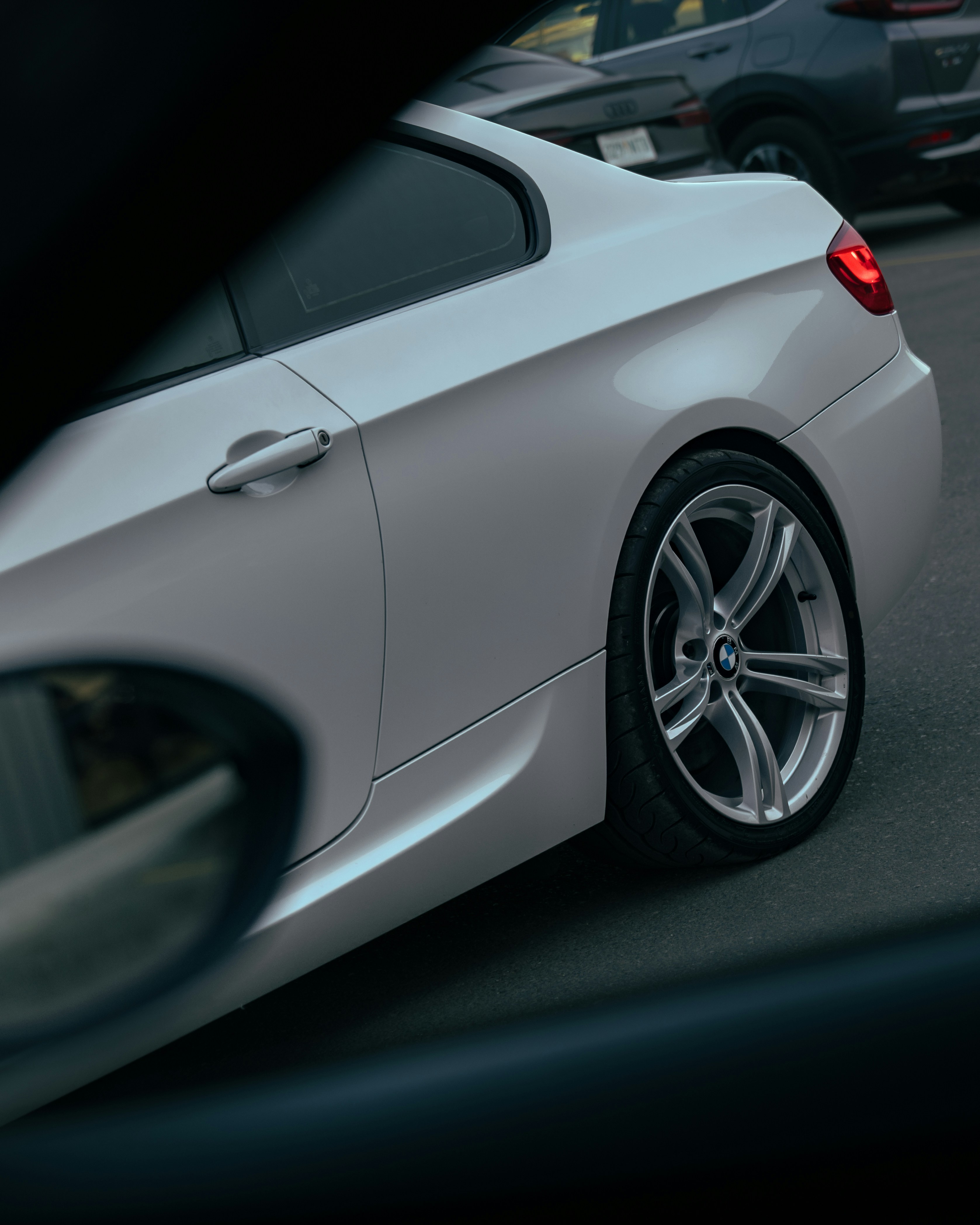 White car parked on a street with other cars.