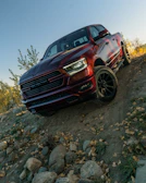 Red pickup truck driving on a rocky incline.