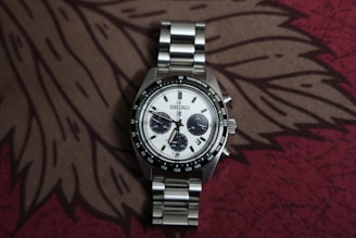 A silver chronograph watch with a white dial.