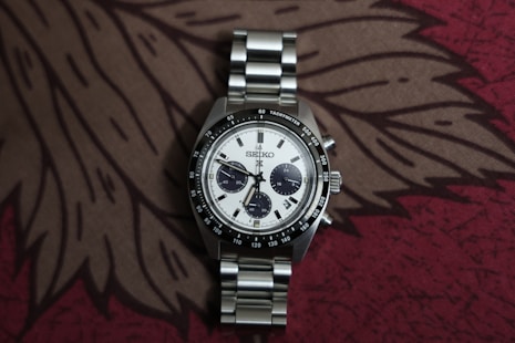 A silver chronograph watch with a white dial.