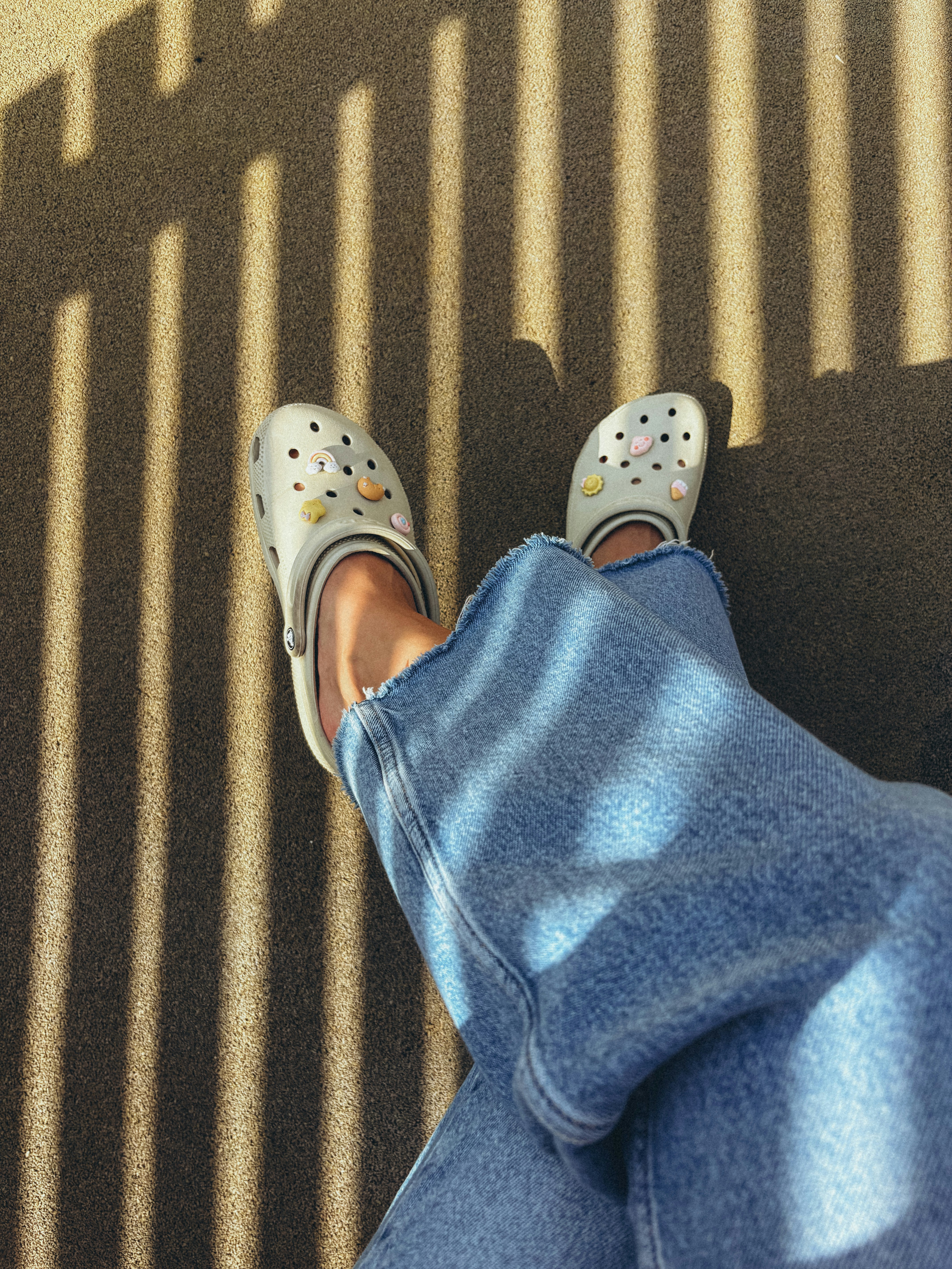White clogs with smiley faces on denim legs