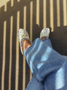 White clogs with smiley faces on denim legs