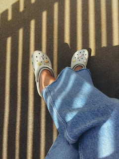 White clogs with smiley faces on denim legs