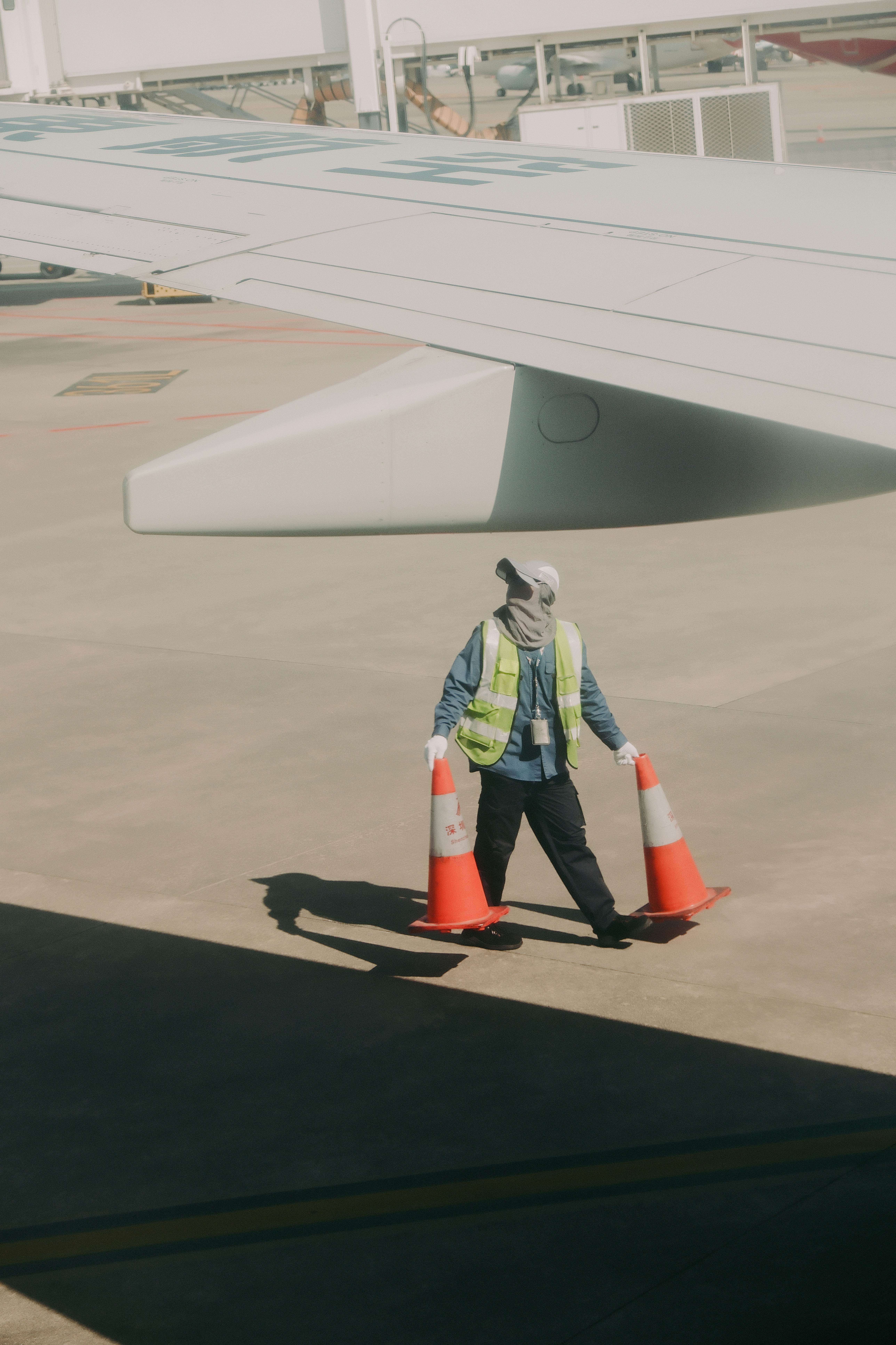 Worker with traffic cones near airplane wing