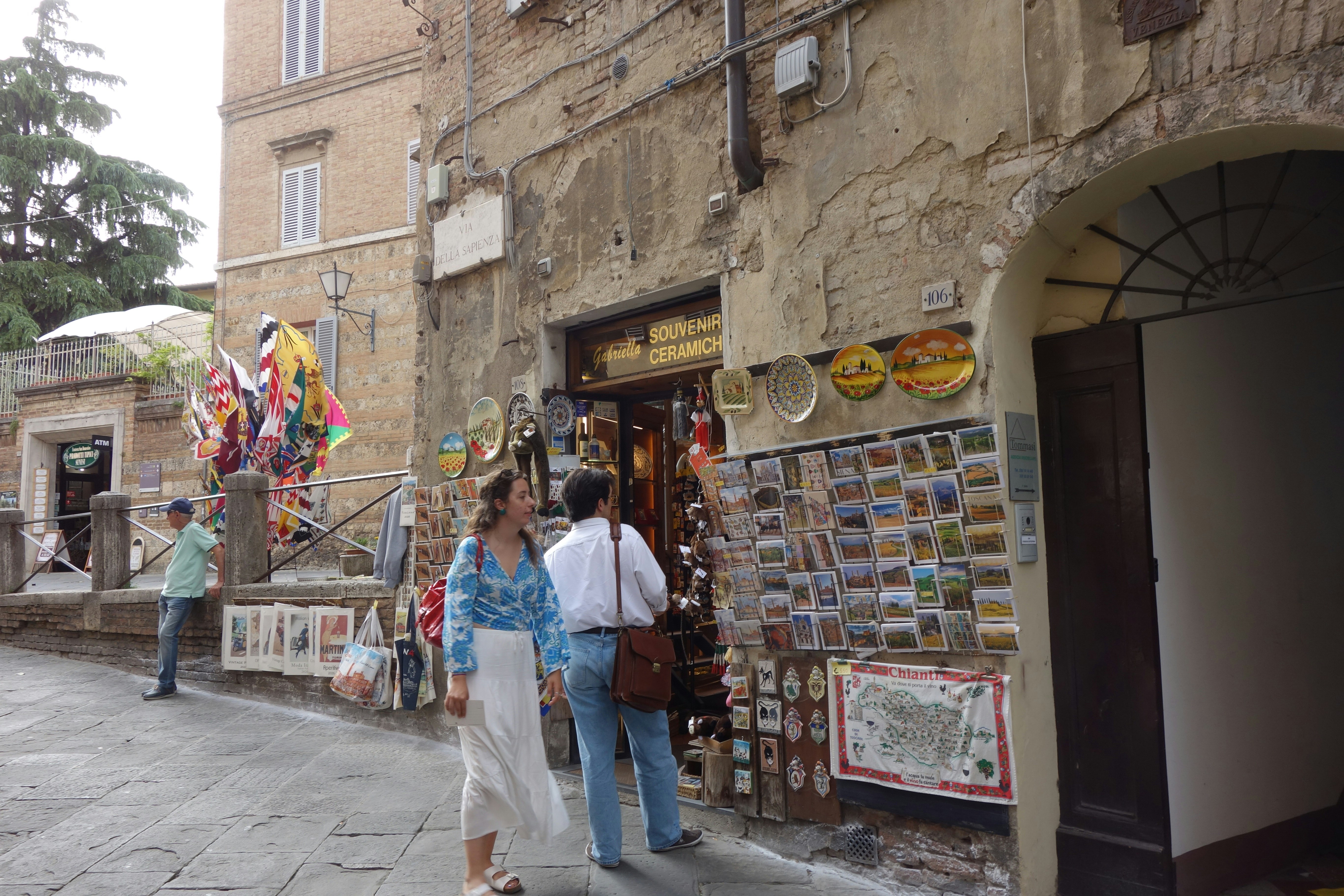 People browse souvenirs outside a shop on a street.