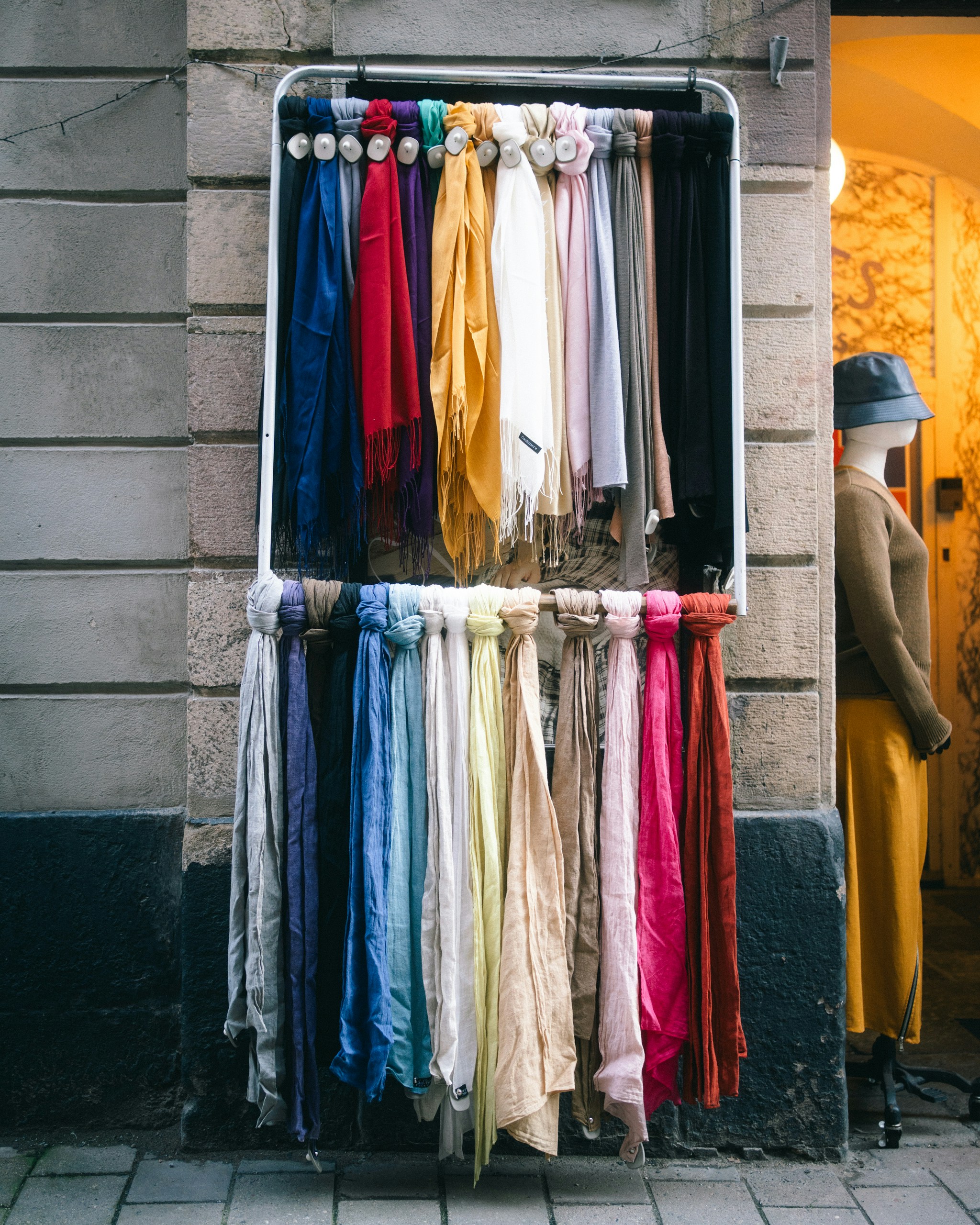 Colorful scarves displayed outside a shop entrance.